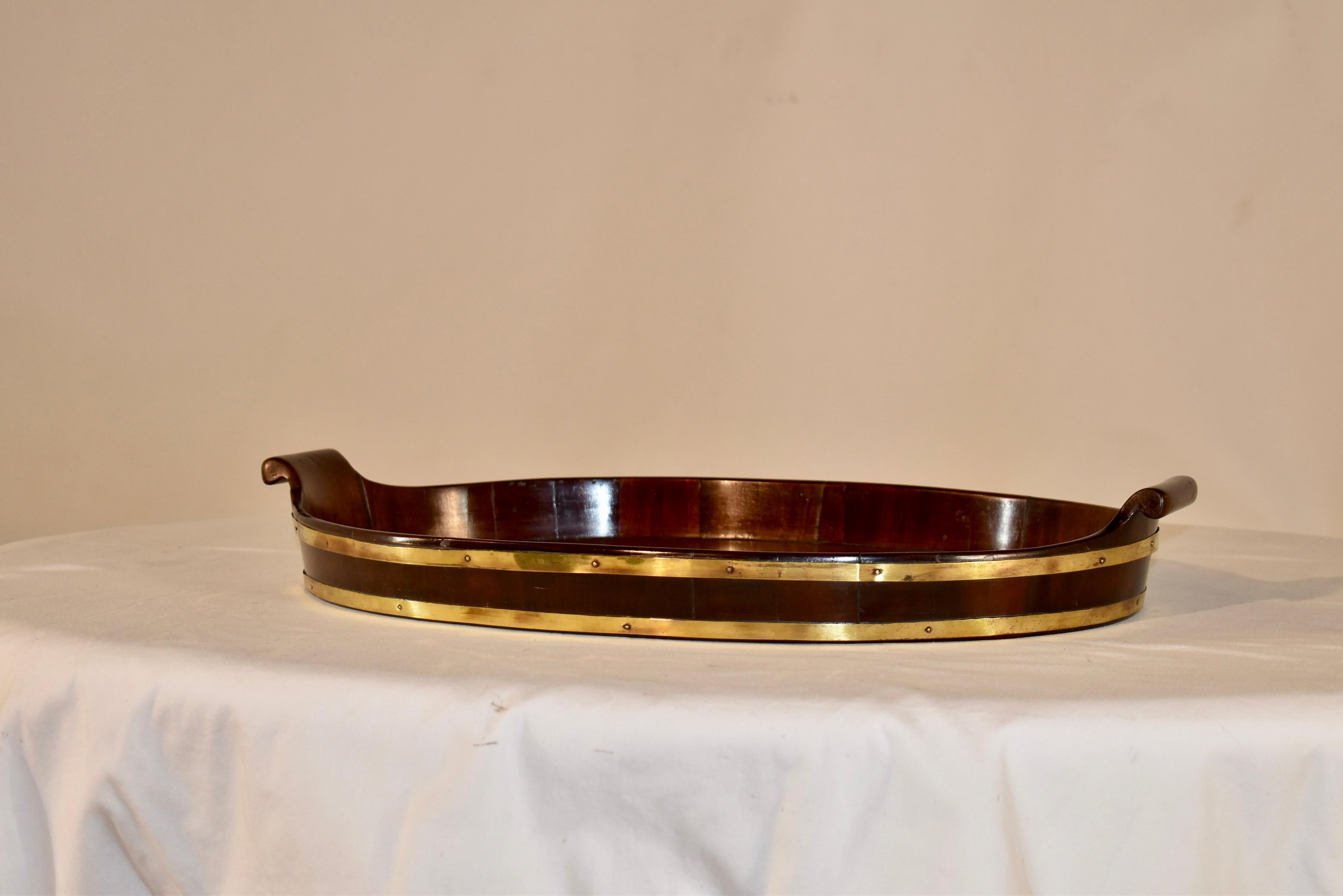 18th Century mahogany tray from England. The tray is made from a single piece of mahogany and the graining is fantastic. The tray is surrounded by a gallery, which is bound by hand made brass strapping. Either end has a hand carved and shaped handle.