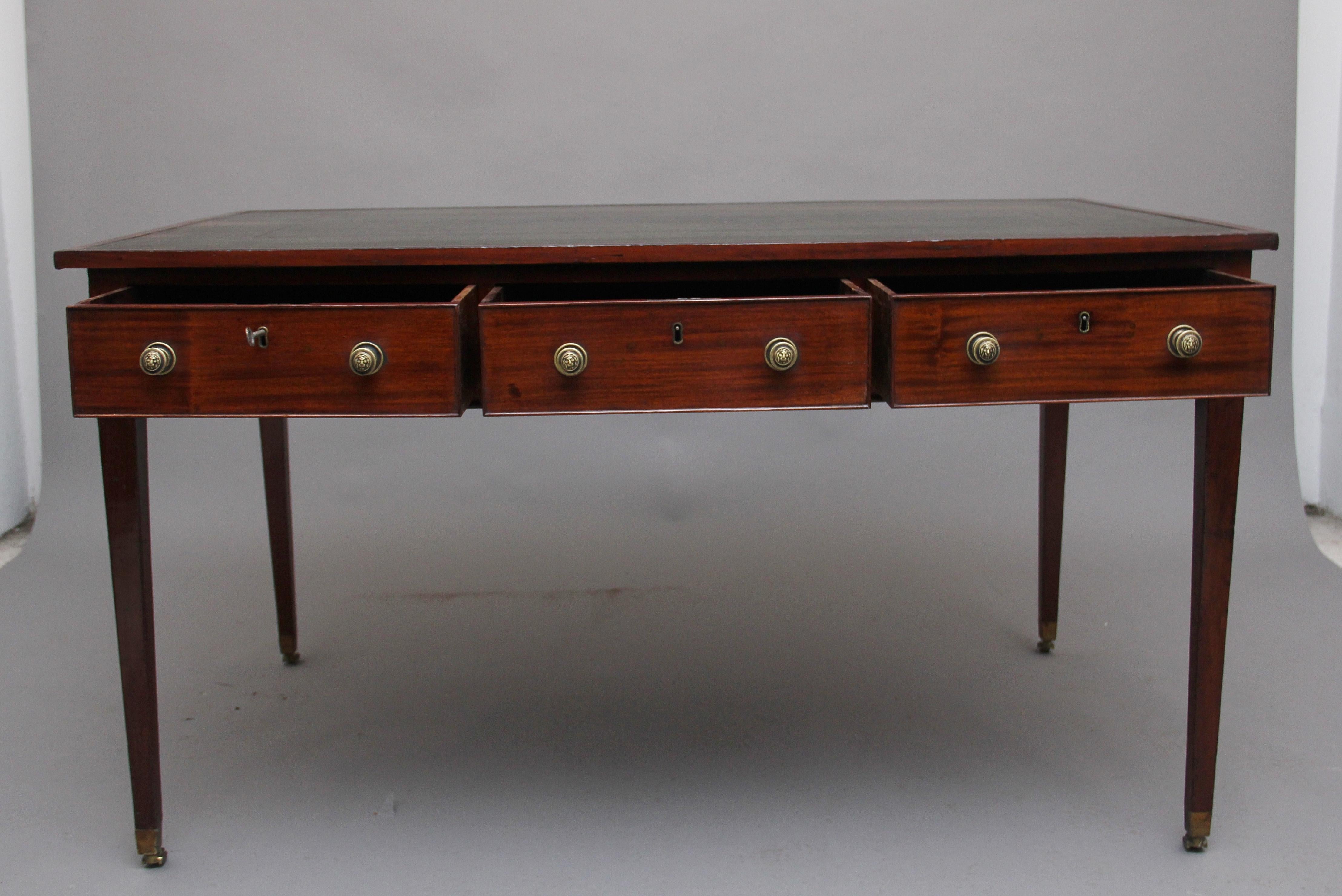 18th century mahogany writing table, having a green leather writing surface decorated with blind and gold tooling, three oak lined drawers with turned brass lion mask handles, the reverse of the table having faux drawers in keeping with the front of