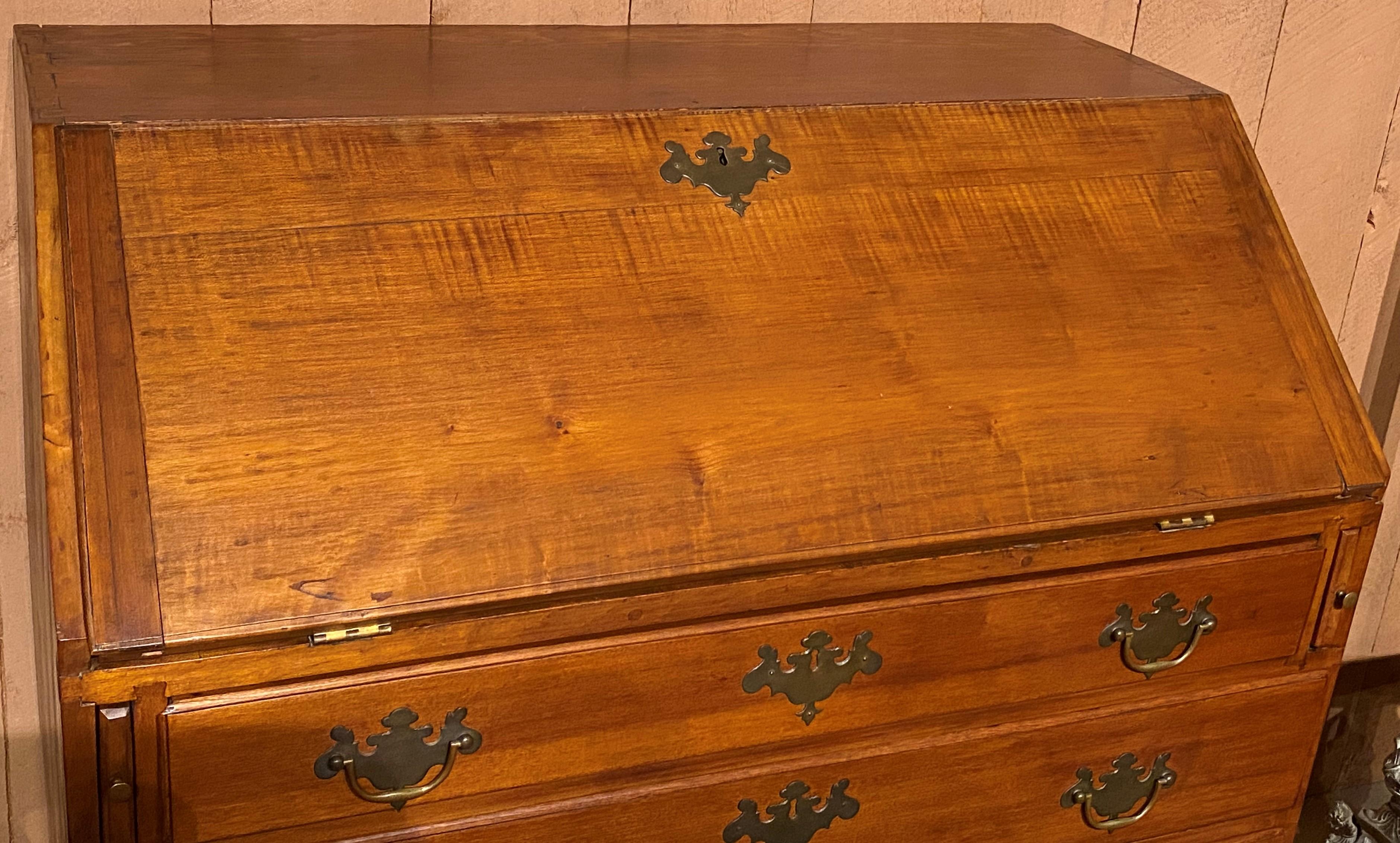 A fine example of a tiger maple and maple slant front desk with compartmentalized interior, including two hidden compartments with faux split column fronts, open valanced cubbies and five fitted drawers, over four graduated long drawers, and