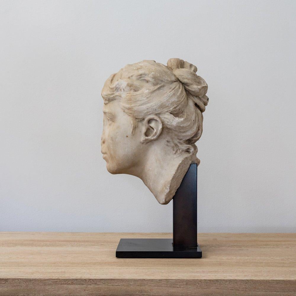 Magnifique buste en marbre d'une jeune femme du XVIIIe siècle. Cette tête sculptée à la main a beaucoup de présence. Il y a tant de détails qui le rendent magnifique.  En commençant par les vrilles de ses cheveux sur la nuque et en terminant par la