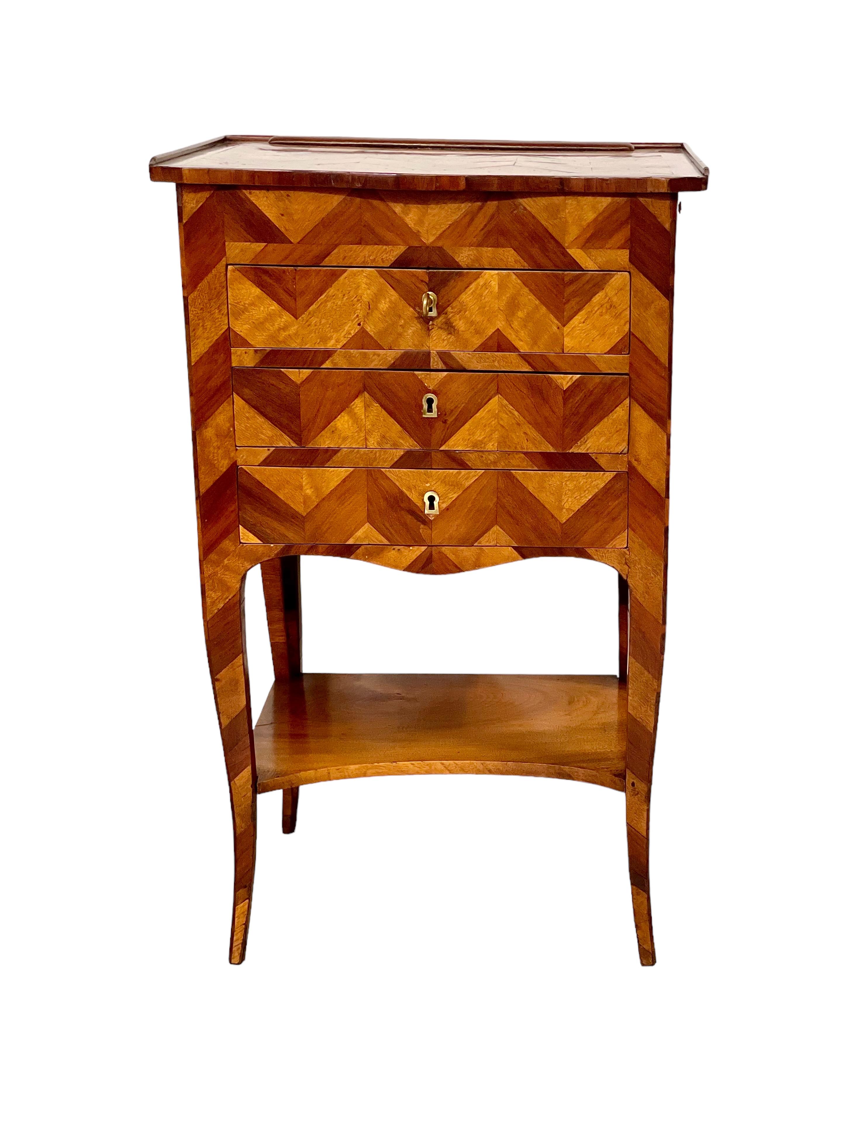 A fascinating and very attractive Louis XV petite commode in veneered wood, with a geometric inlaid marquetry decoration. Three slim drawers open to the front, with another to the side, providing lots of useful storage space. The most intriguing