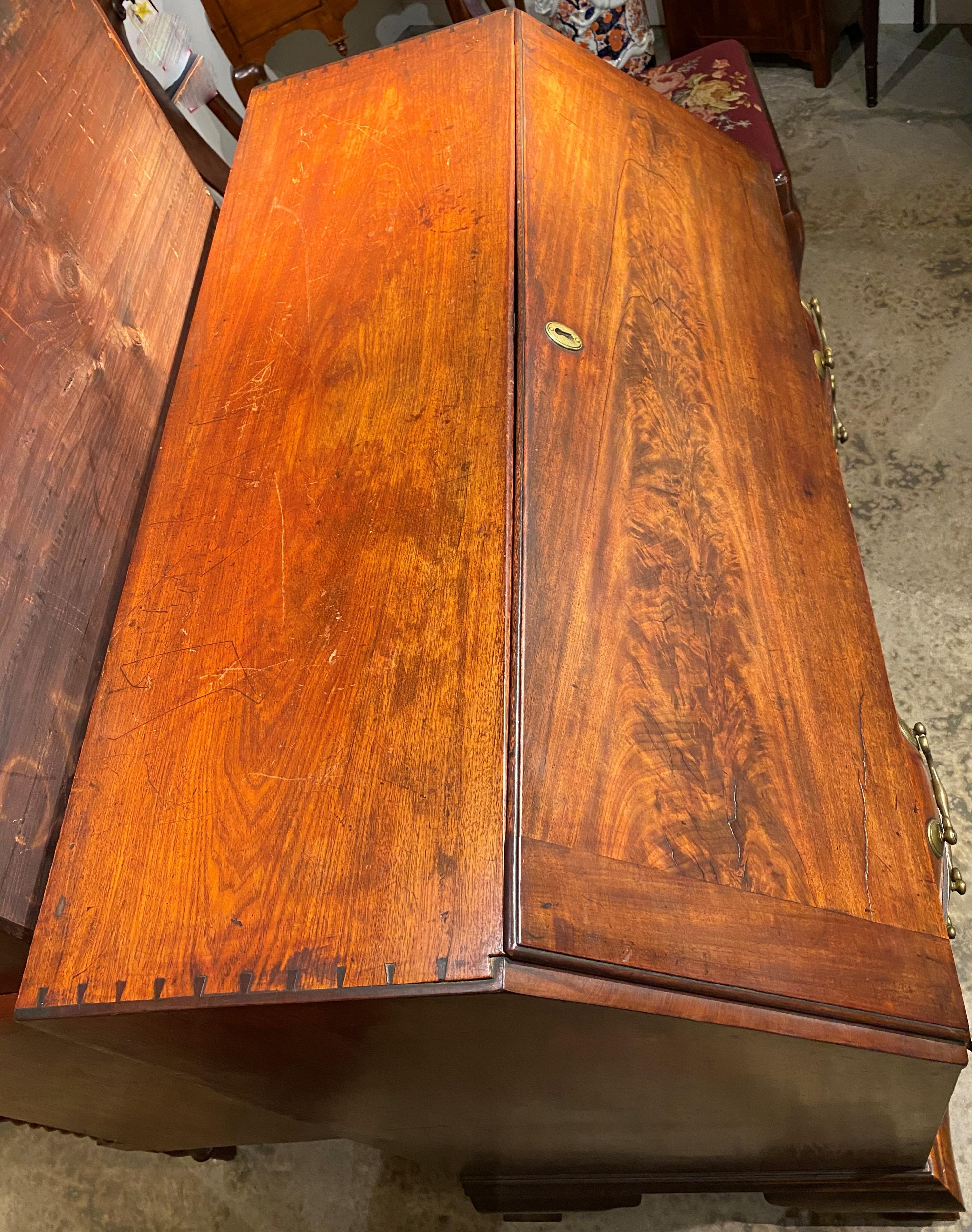 A fine mahogany Chippendale slant front desk with serpentine case, dovetailed construction, compartmentalized interior with fan carving, valanced open cubbies and fitted drawers, over a well-used writing surface, four long drawers with original