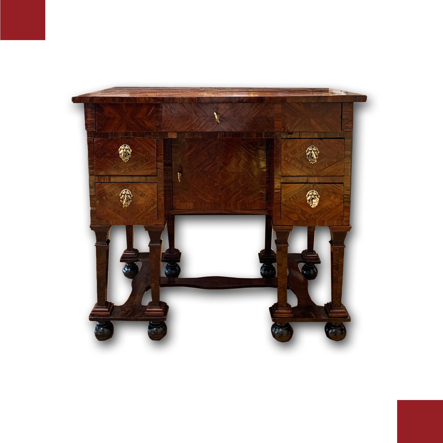 Elegant desk with folding top, supported by a base with truncated pyramid legs joined by crosspieces. The desk is completely veneered in rosewood, which gives it high refinement. The handles are made of bronze, of which those of the front drawers