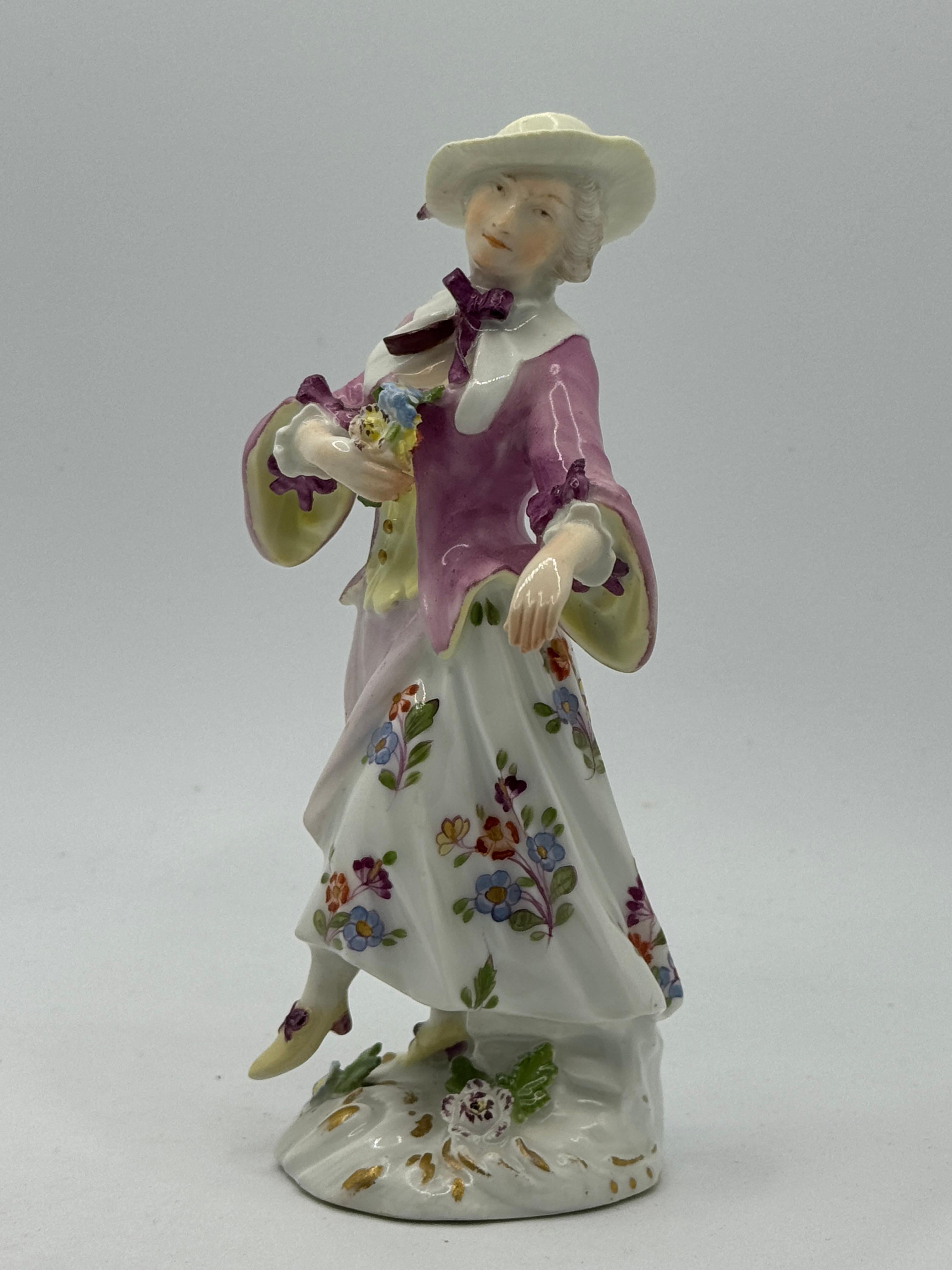 Buena figura de dama de Meissen del siglo XVIII, hacia 1740, modelada por Peter Reinecke con sombrero con lazo, vestido de flores y un ramo de flores en la mano, sobre una base con incrustaciones florales. Tenue marca azul de espadas cruzadas en la