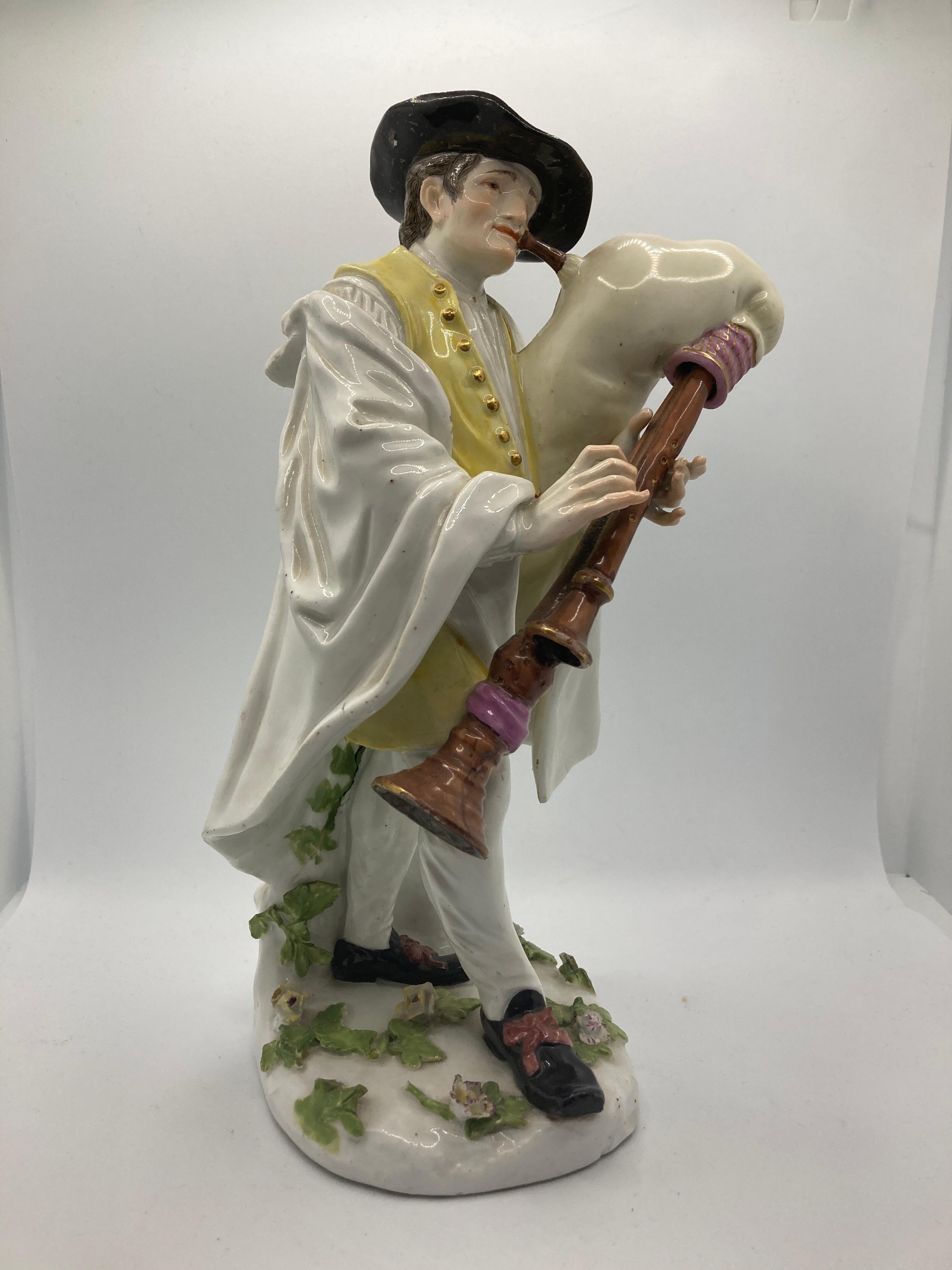 18th Century Meissen Porcelain Figure, Piedmontese bagpiper.  

Modelled by J.J. Kändler after an engraving by Jacques Dumont, wearing a black hat with brown feather, fur-lined white cape, yellow waistcoat with Sgraffito scrolls and circles and