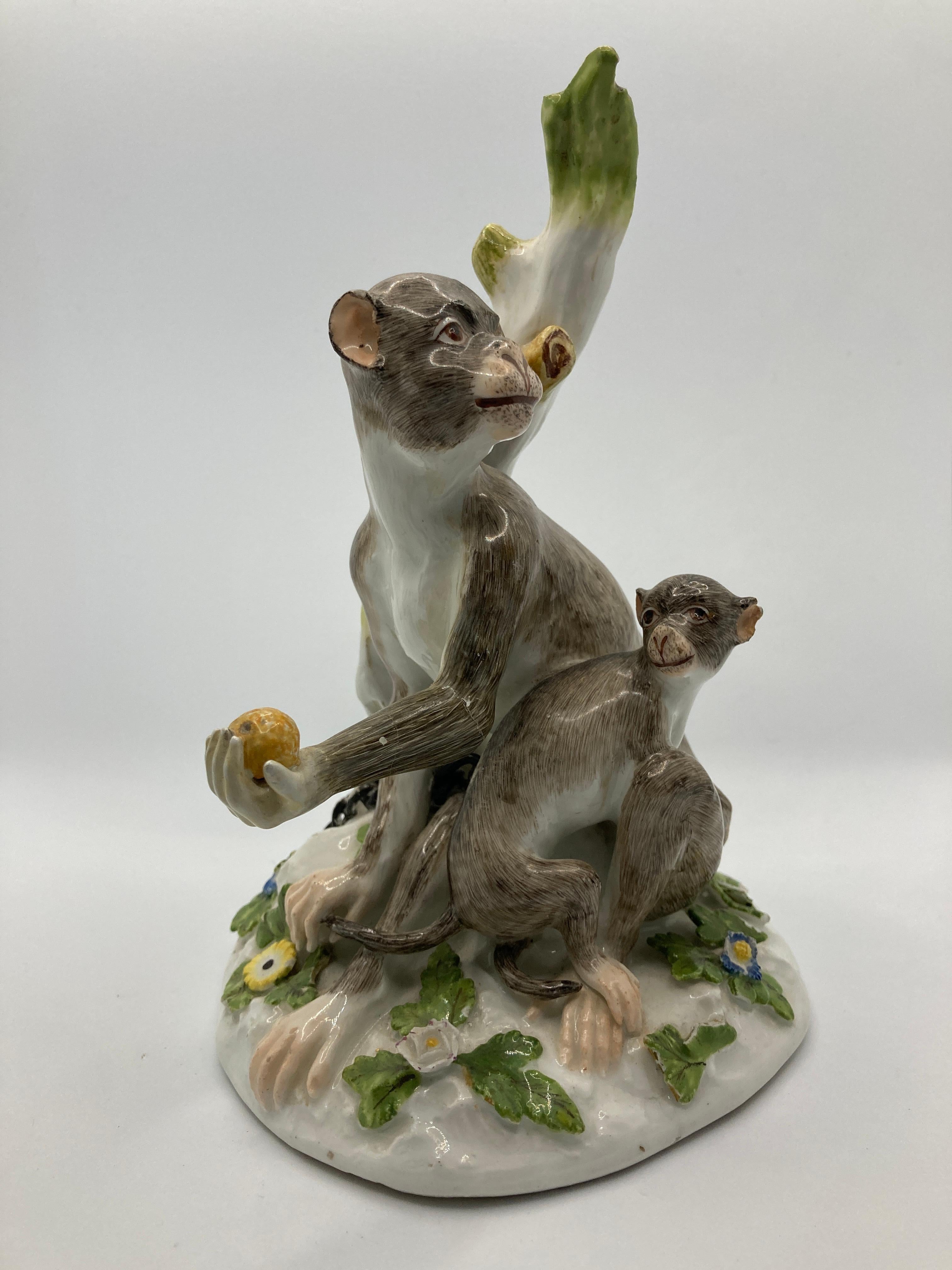 18th Century Meissen Porcelain Figure, Rhesus Monkey and child, model 1464, circa 1750 .  

Modelled by J.J. Kändler. Monkey, with outstretched hand holding fruit, and child chained to a tree stump, sitting on an oval mound base applied with flowers