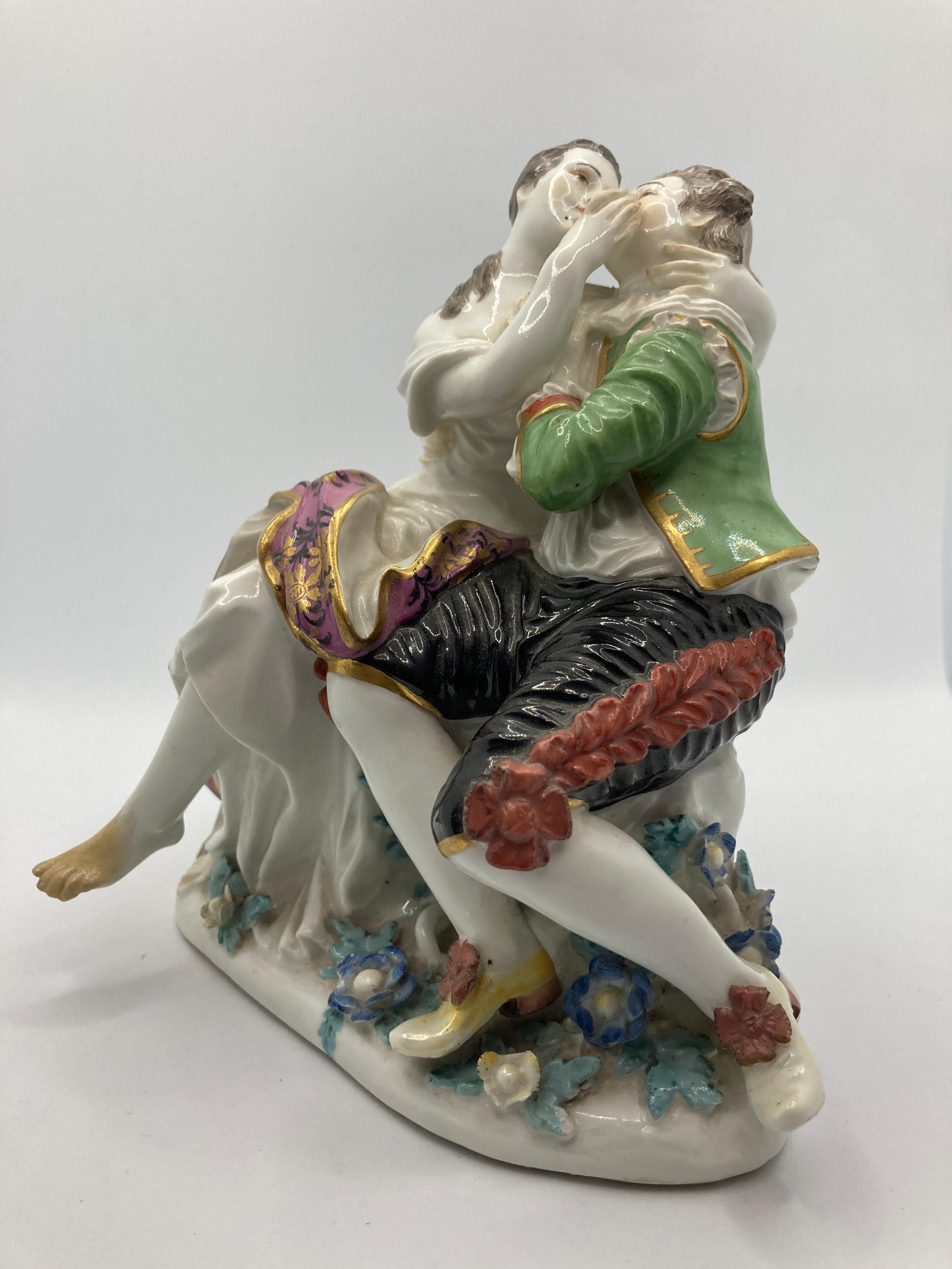 18th Century Meissen Porcelain Figurines, Pair of Lovers. Model 571. 

Sitting lovers, designed by Johann Joachim Kaendler, above a base covered with plastic flowers and leaves, shepherd couple sitting on a tree stump, kissing and embracing each