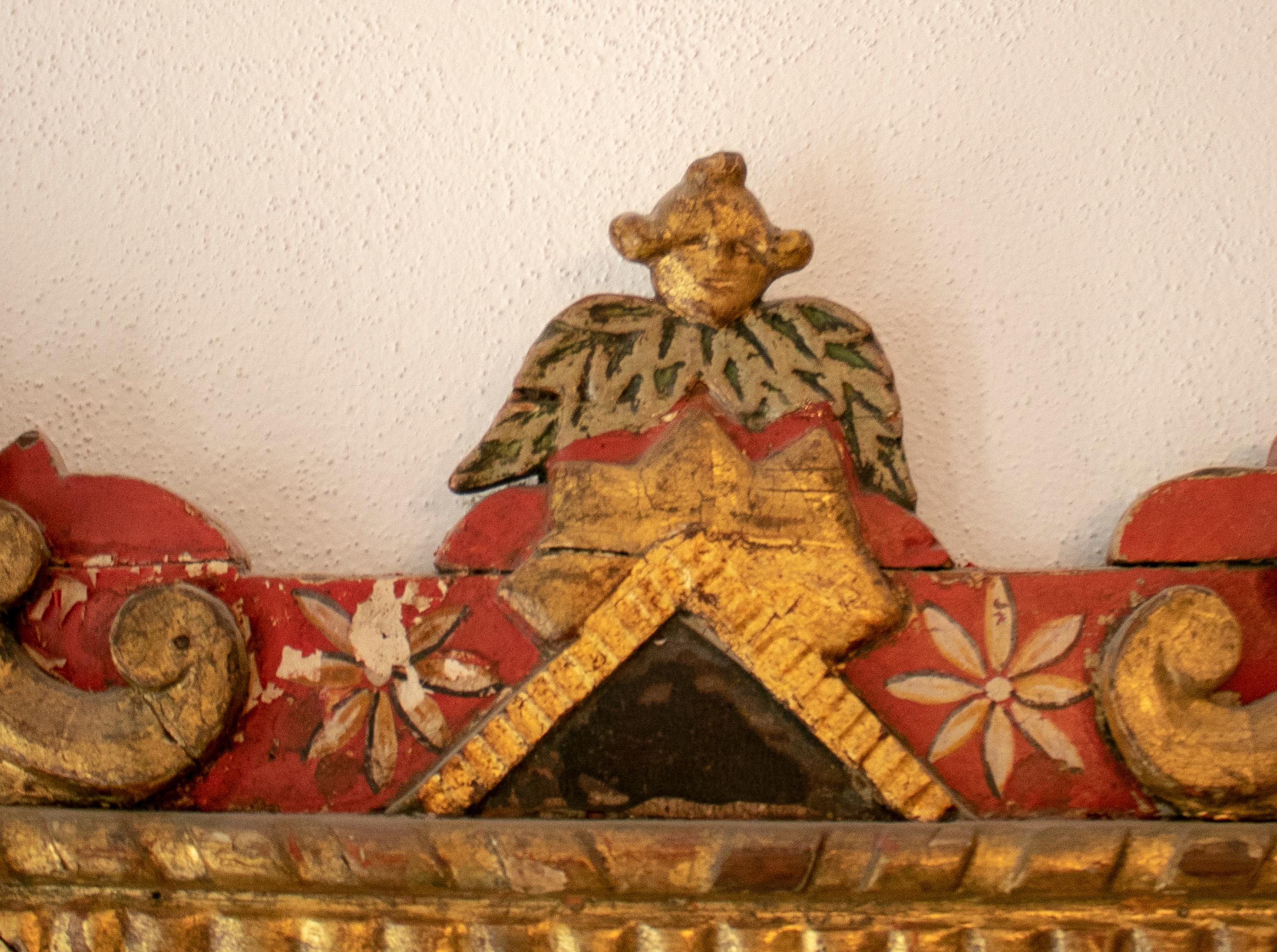 18th century Mexican mirror with hand carved painted wooden frame, in red and golden colors.