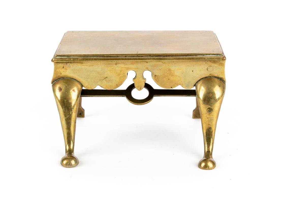 18th century miniature brass trivet with scalloped apron, cabriole front legs, back legs resting on spear feet, cross stretcher base with center ring.

Dimensions: 5