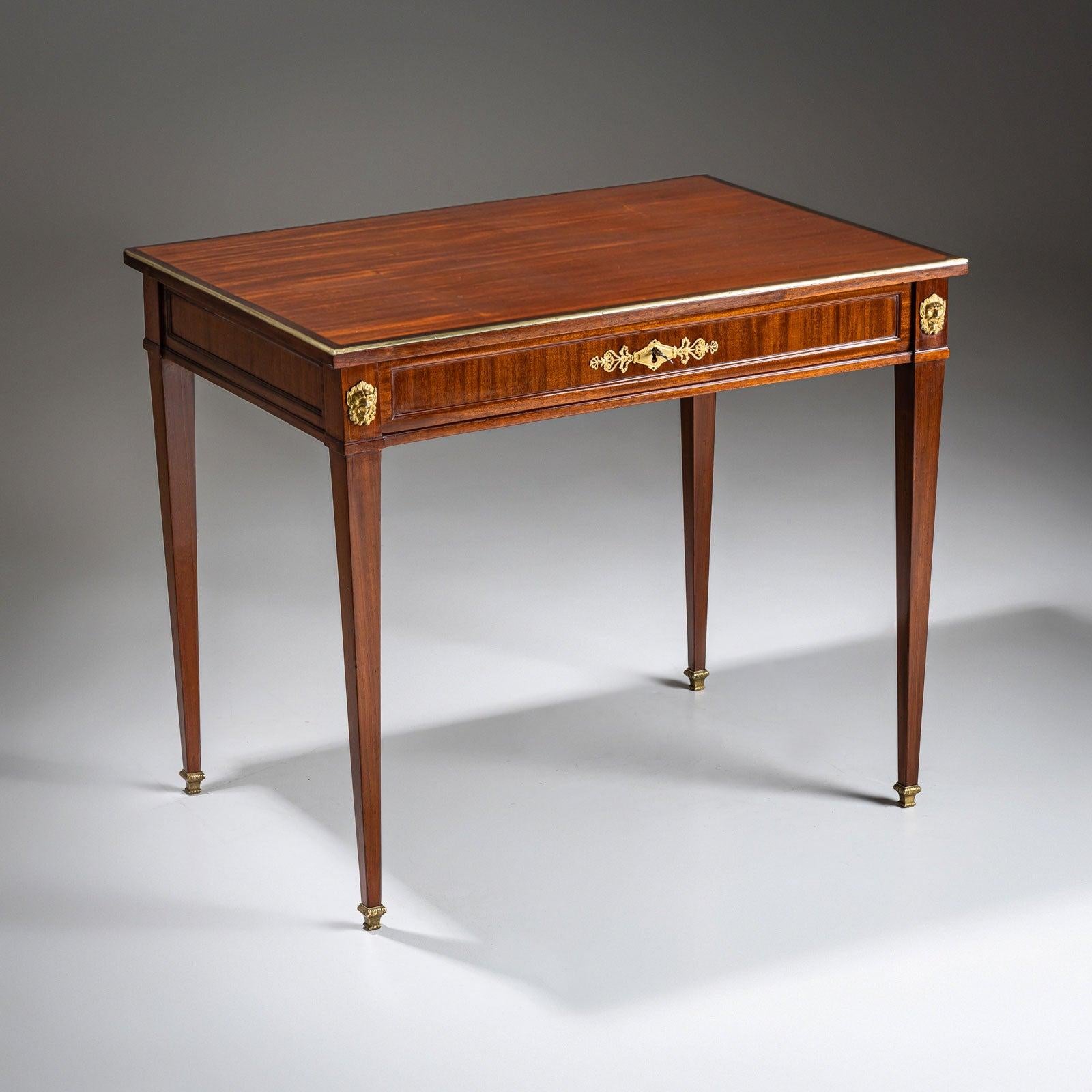 An elegant Neoclassical desk featuring one drawer and a sliding tabletop. The piece is beautifully veneered and hand-polished. It stands on tall tapered square legs, accented with bronze sabots. The interior includes a writing surface covered in