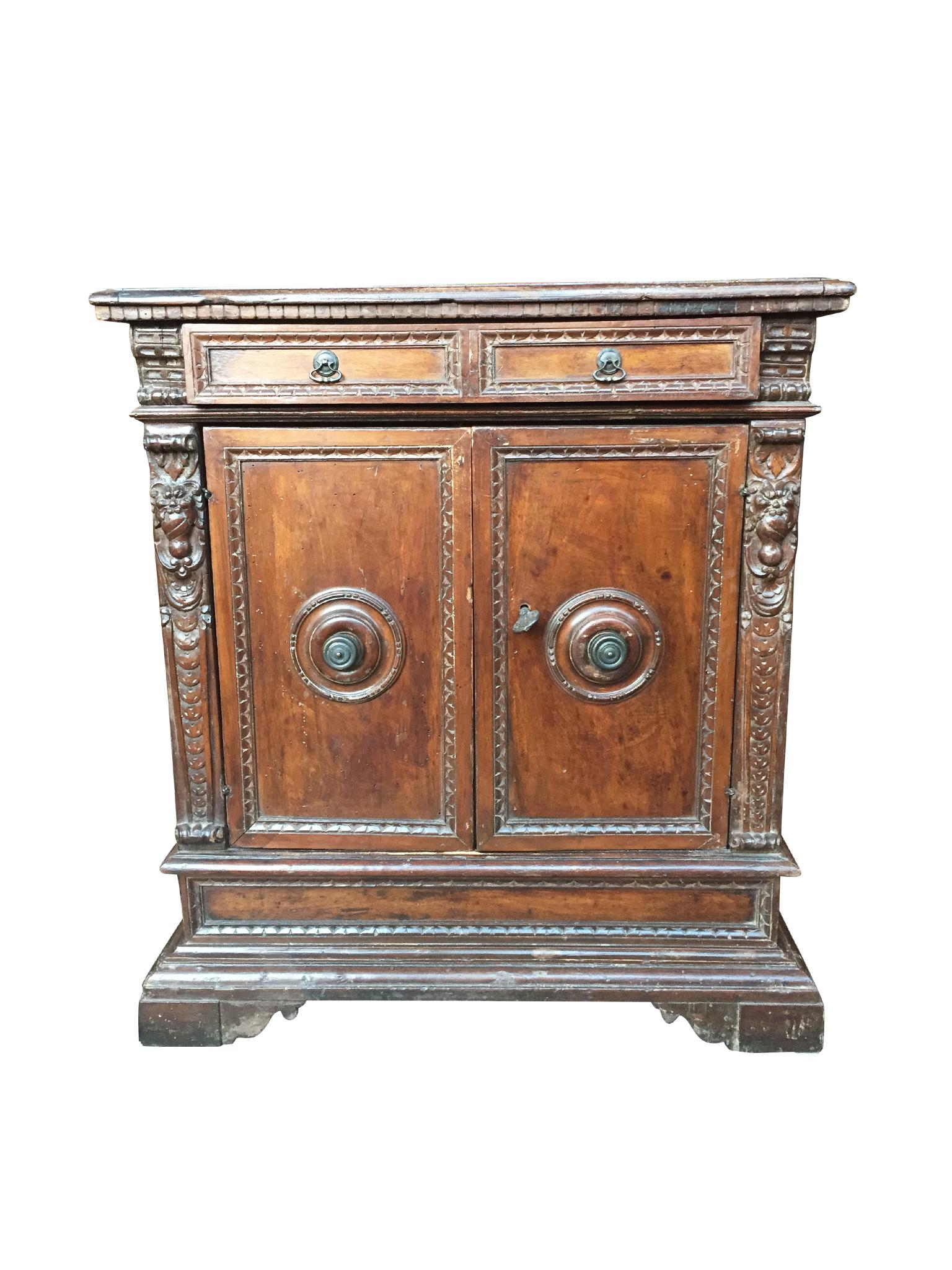 This handsome Italian cabinet was handcrafted in the 18th century. It is comprised of walnut wood with carved decorative trimming and iron hardware. The cabinet is a flattop with a single top drawer. The main body is designed with two doors that