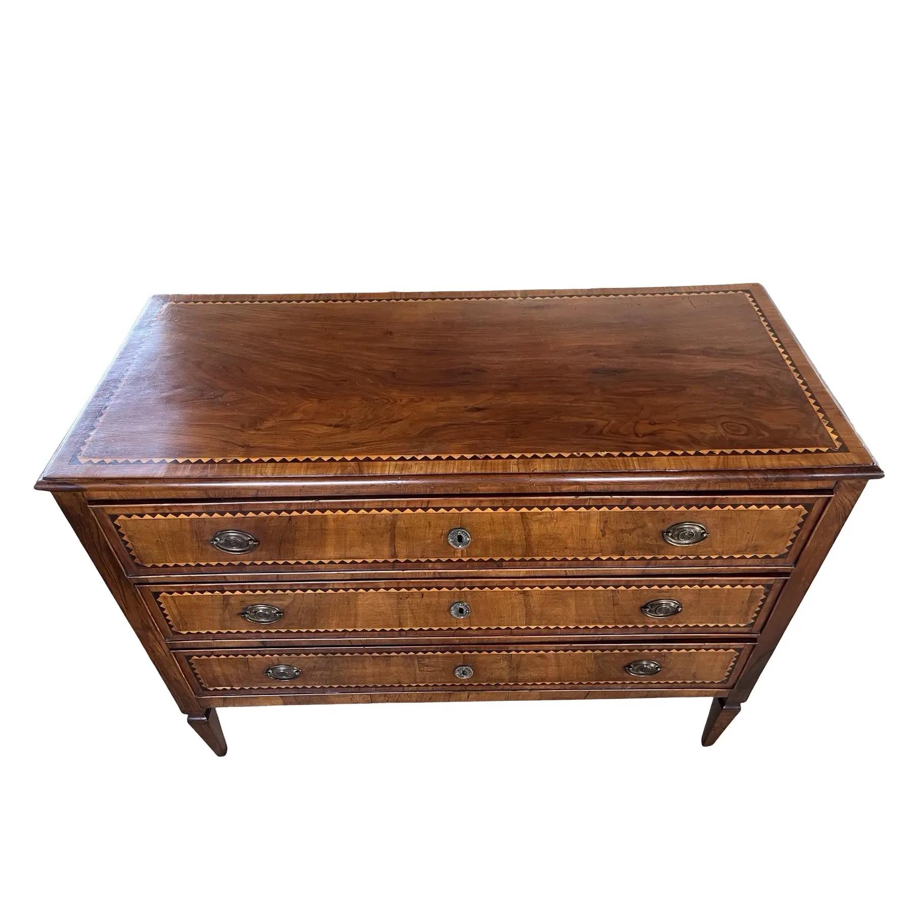 Cassettone realizzato a mano in Italia alla fine del 1700 con ciliegio e decorato con impiallacciatura in noce e intarsio ebanizzato. La cassettiera presenta le tipiche linee rette delle commodes neoclassiche italiane, con lunghe gambe affusolate e