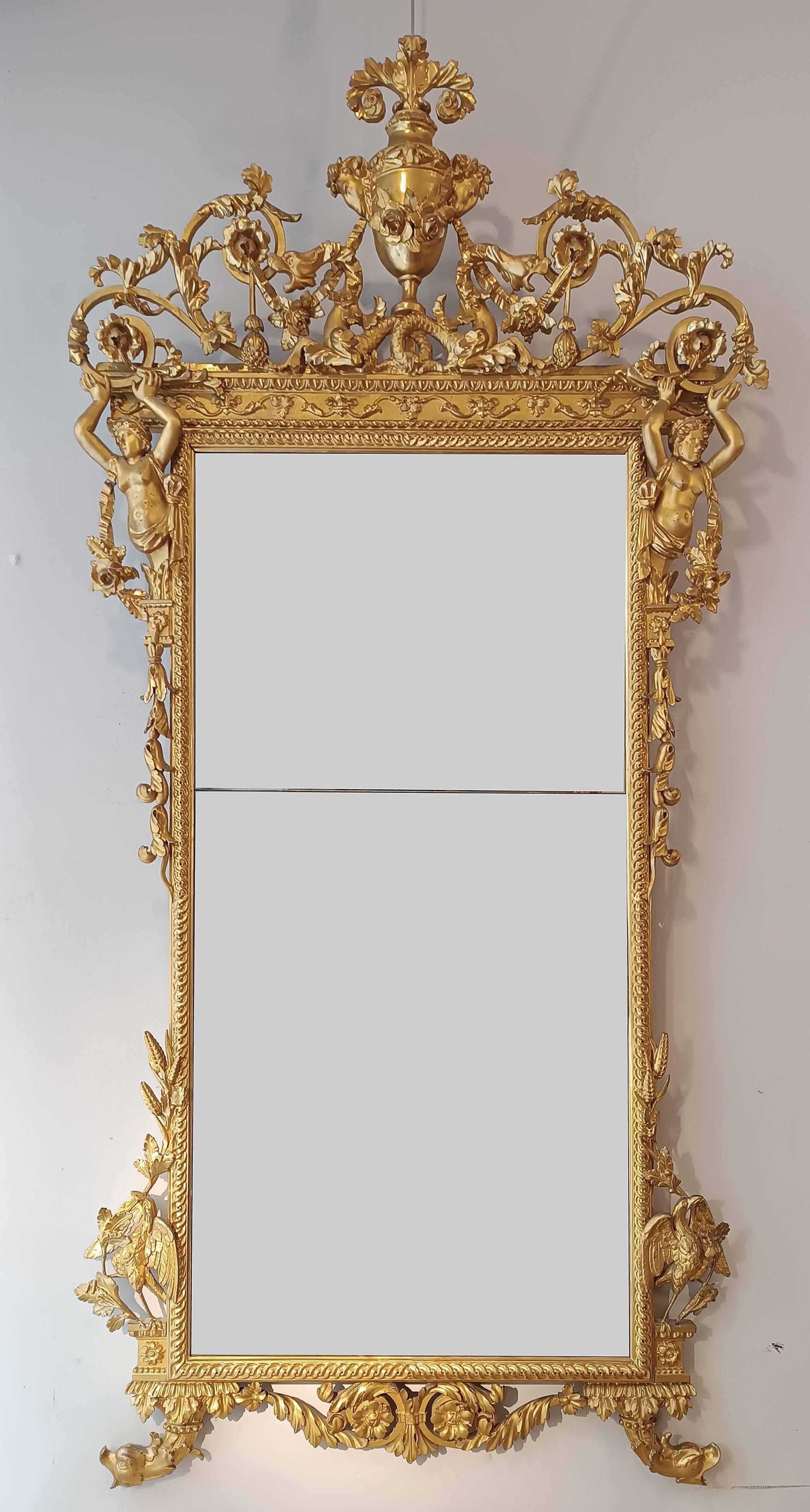 This refined mirror is made of carved pine wood and subsequently gilded with pure gold leaf, giving it an extremely elegant appearance. Every detail is taken care of down to the smallest detail, from the small feet with zoomorphic heads to the large