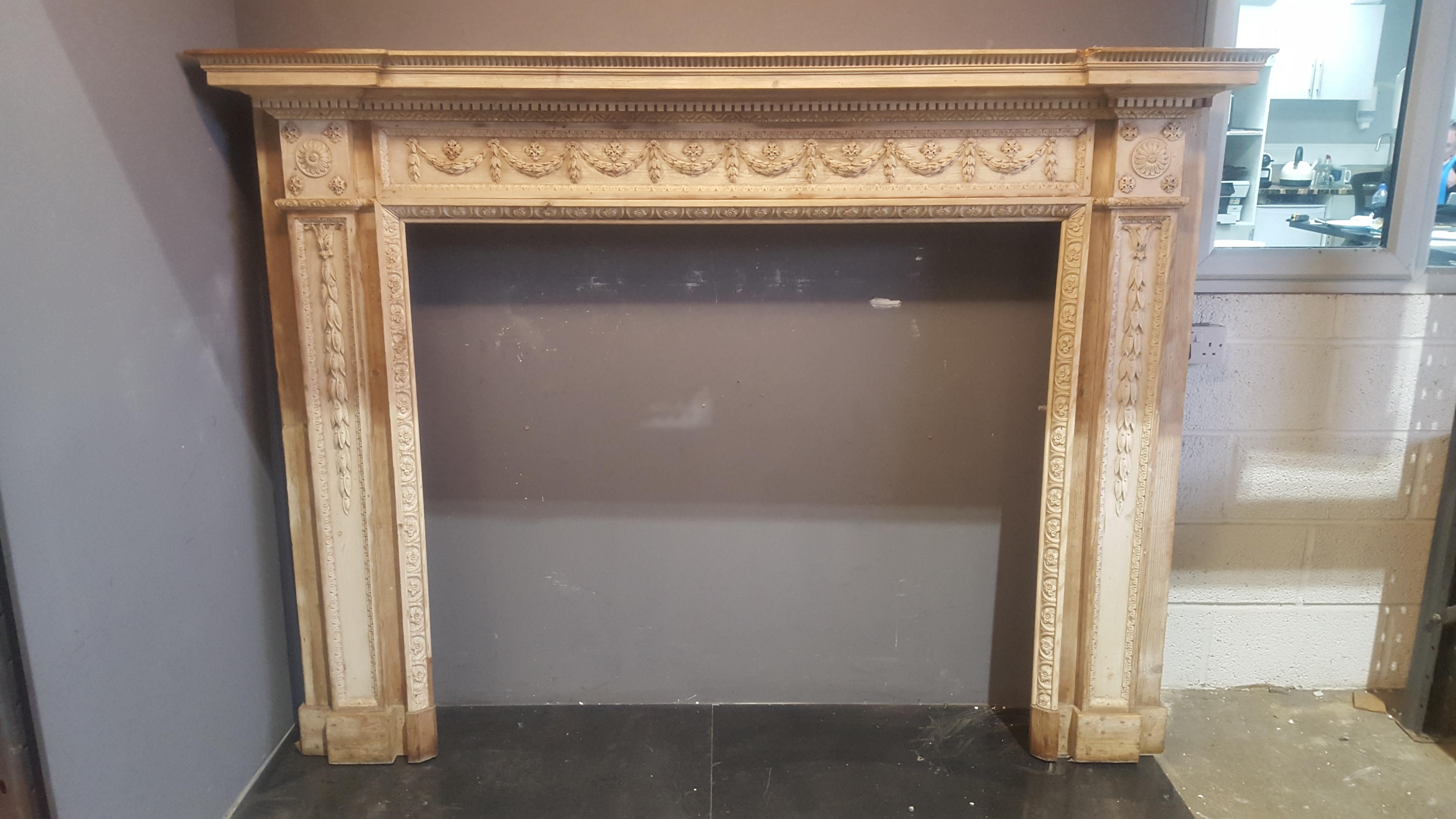 A very fine late 18th century neoclassical pine mantel in excellent condition and exquisitely well carved featuring corner blocks carved with rosettes above tapering pilasters carved with pendant bell drops, and running frieze ribbon tied swags