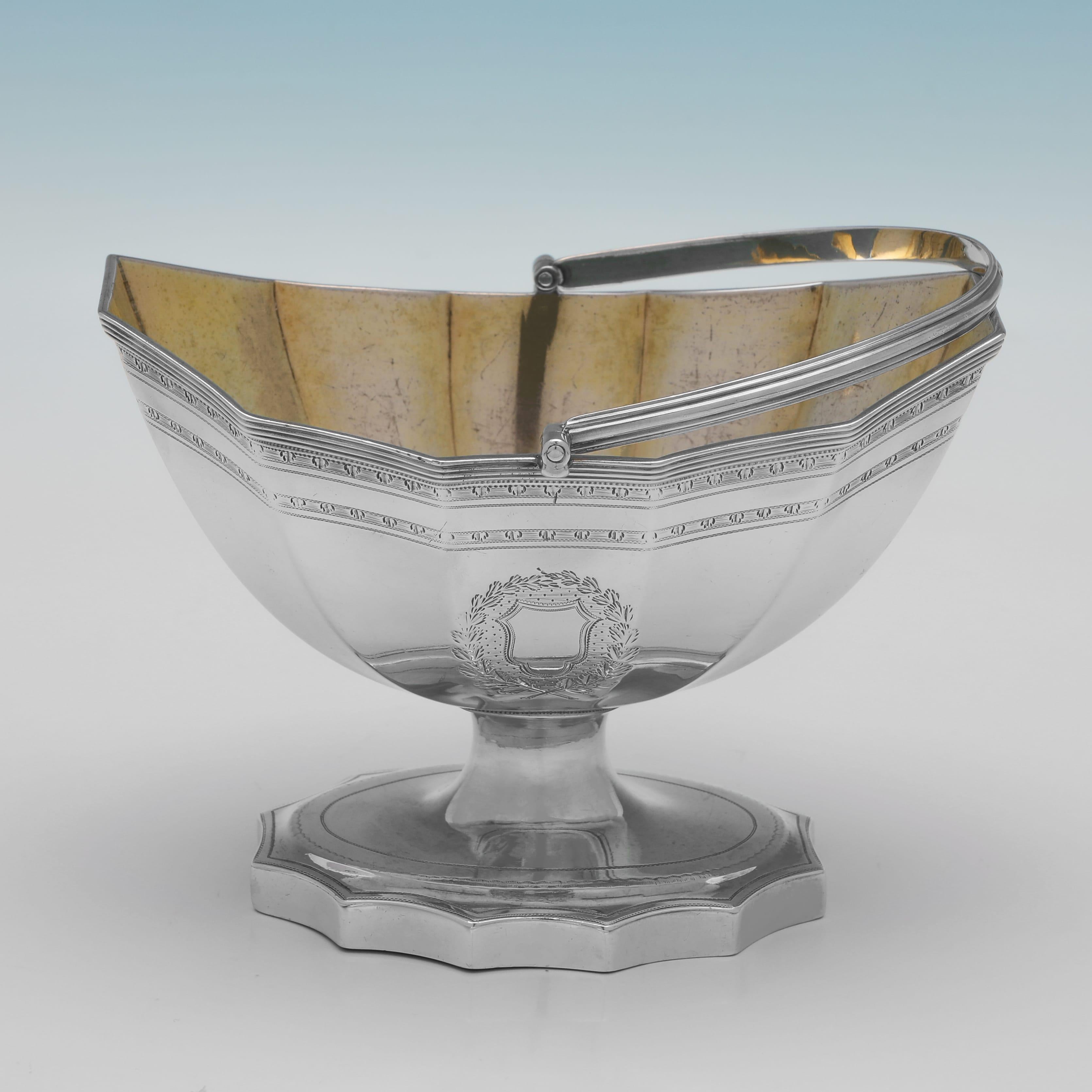 Hallmarked in London in 1792 by Henry Chawner, this attractive, George III period, Antique Sterling Silver Sugar Basket, is in the Neoclassical taste, featuring bright cut engraved decoration throughout, an engraved crest and a gilt interior. 

The