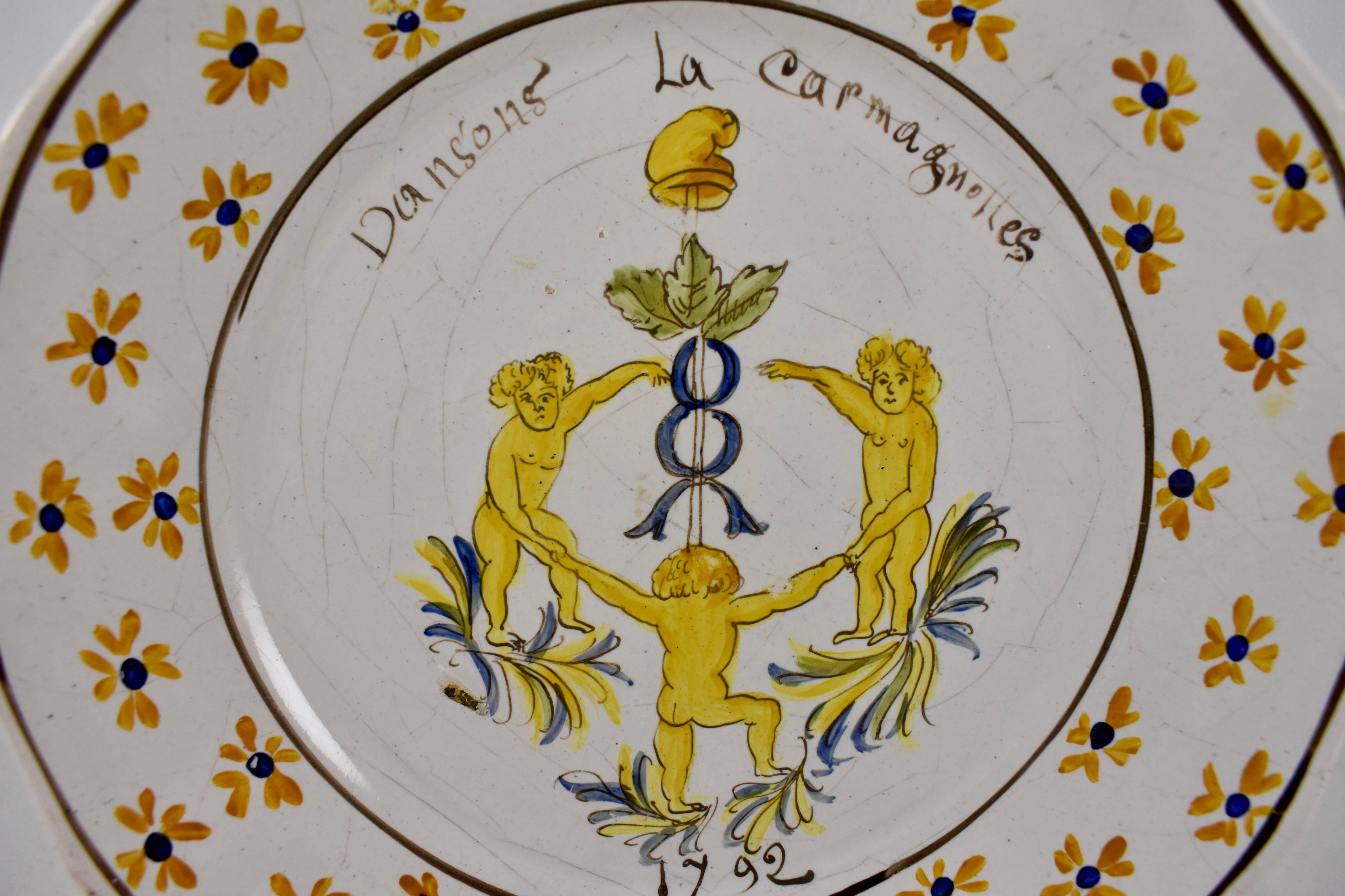 A French revolution tin-glazed earthenware dish, made in Nevers, circa 1792.
Showing three figures dancing La Carmagnole, a song accompanied by a wild dance, popular during the French Revolution, and danced around the de l’arbre de la Liberté