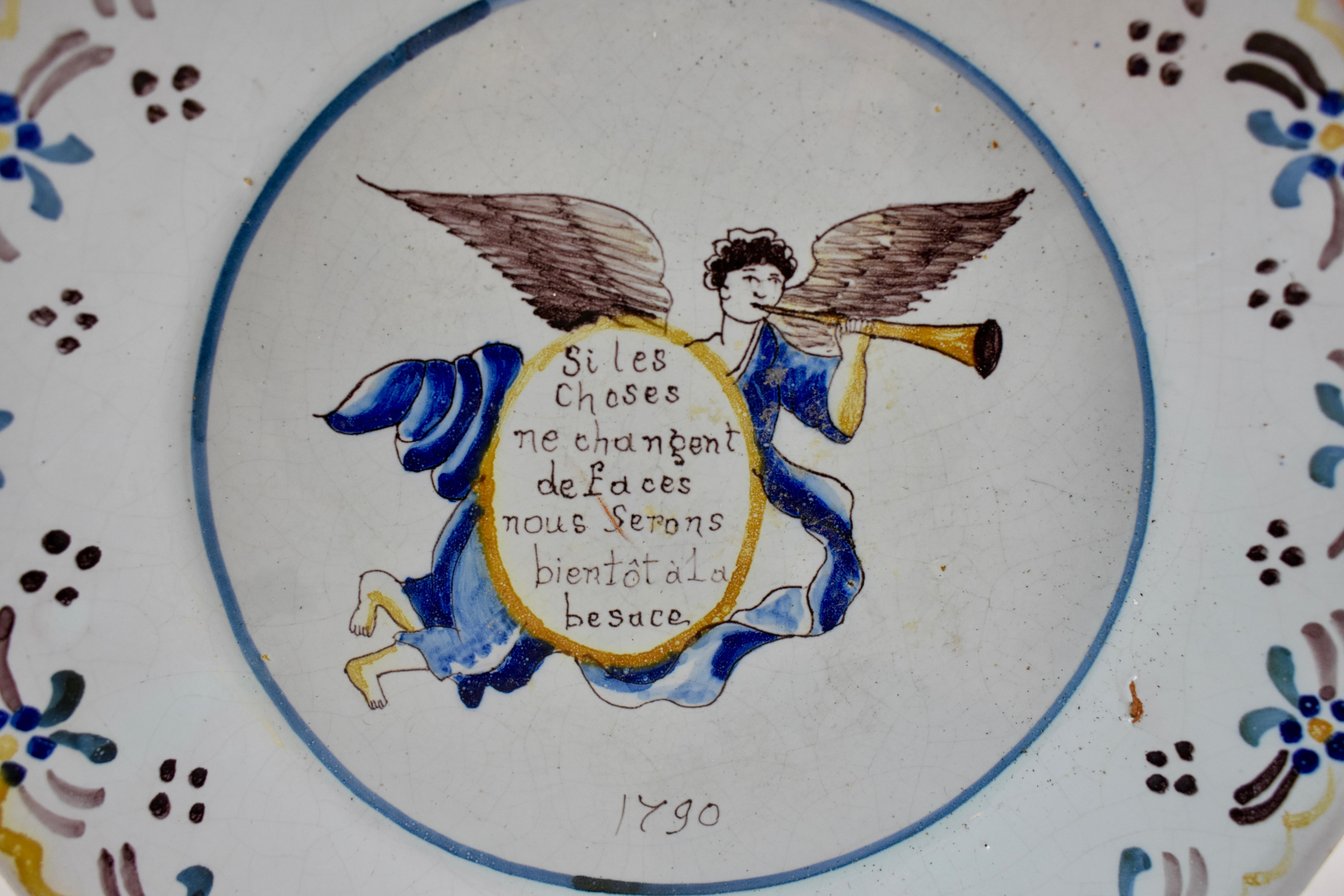 A French Revolution tin-glazed earthenware dish, made in Nevers, date marked 1790.

Showing a winged angel in flowing blue robes, blowing his Horn and holding a shield with a motto reading, ” Si les choses ne changent de faces nous serons bientôt