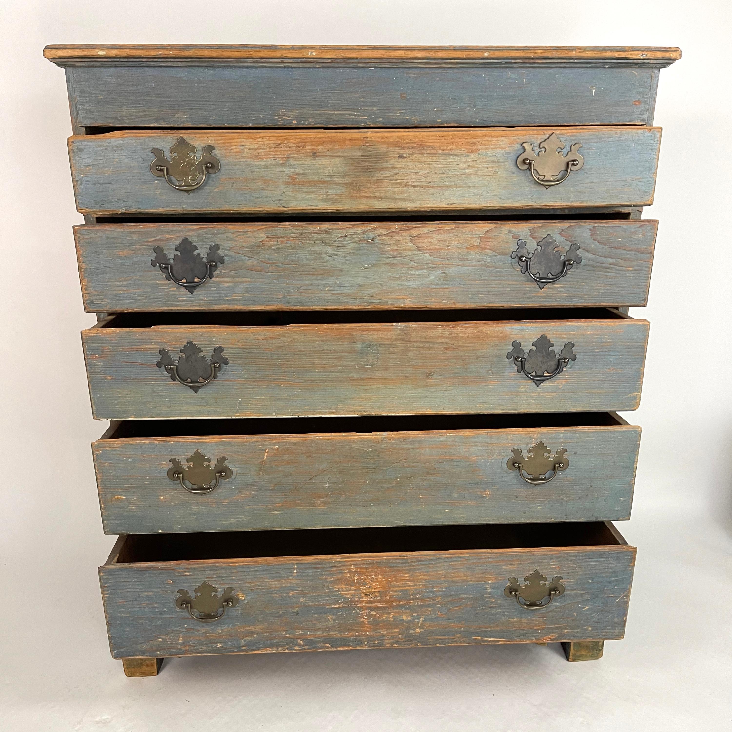 An 18th century New England blue painted chest of drawers in pine, the moulded top over five graduated thumb-moulded drawers, with bats wing brass pulls, all raised on an old, but later, base with bracket feet.
An early piece, with great character