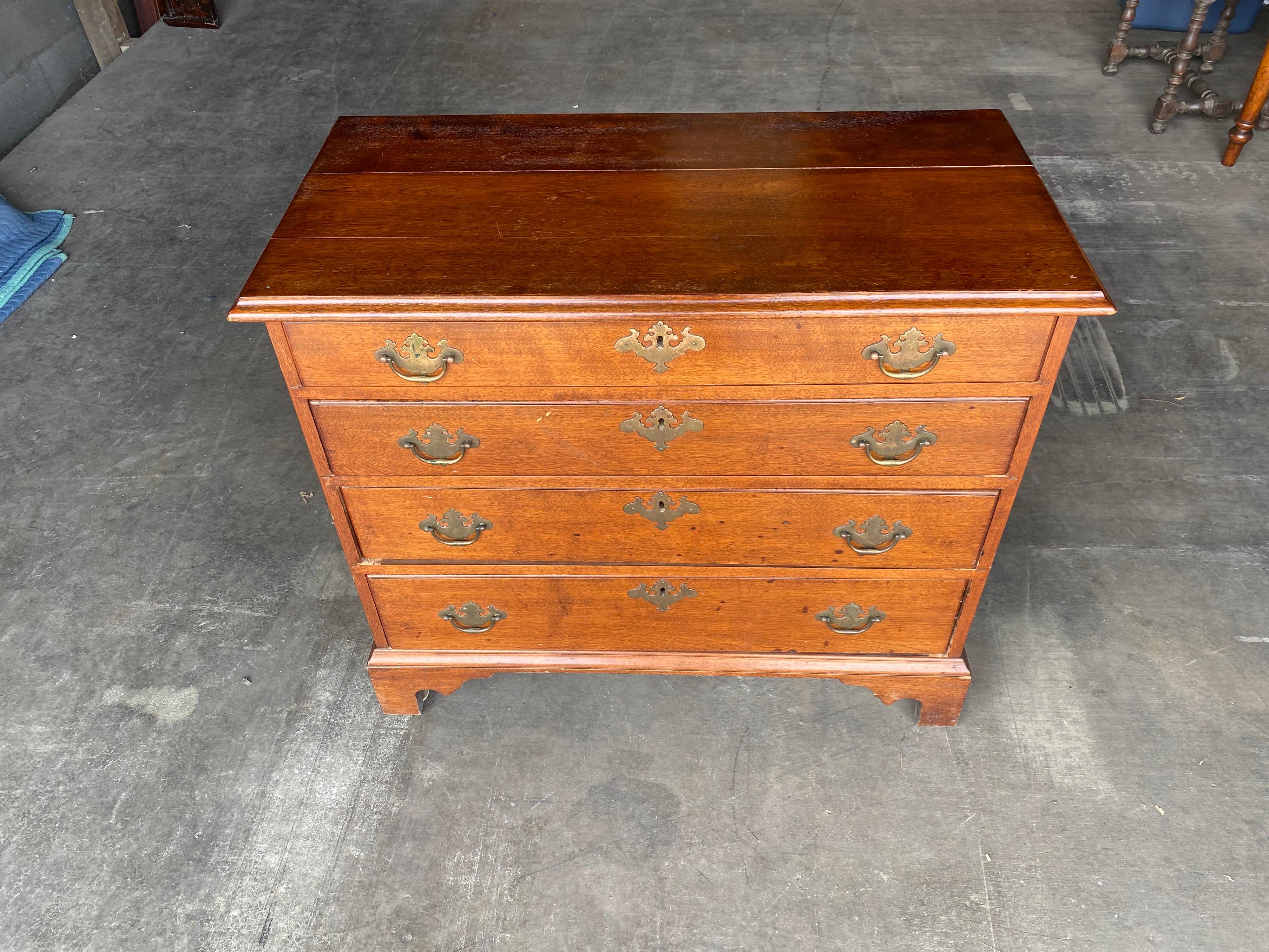 18th century New England mahogany four drawer chest with bracket feet and original hardware. Two board top.