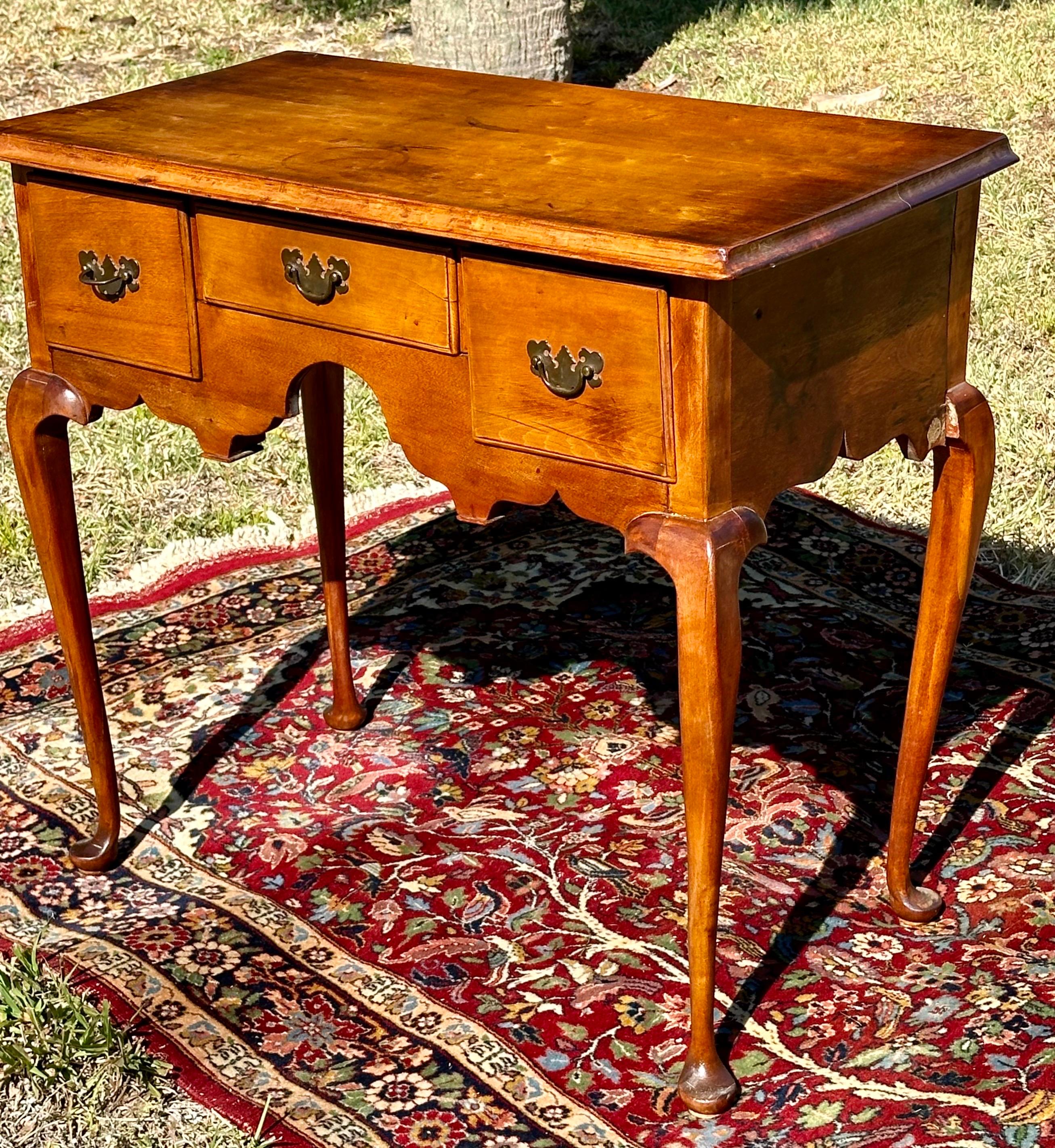 18th Century New England Queen Anne Cherry Lowboy

American cherry Lowboy with elegant scalloped apron from the Queen Anne period, about 1760. The top has a molded edge above three drawers. The center drawer is flanked by two deep drawers. The