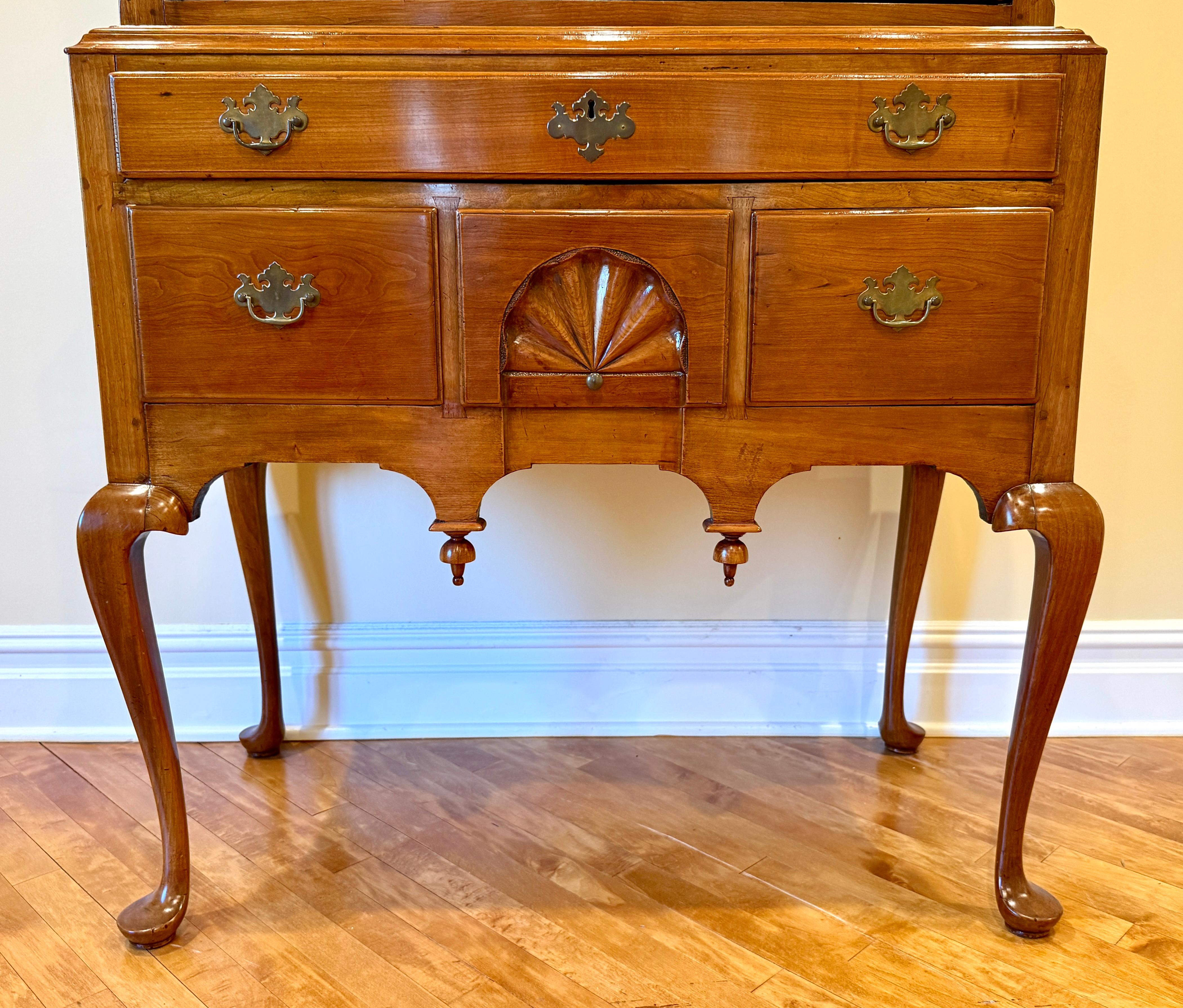 Queen Anne bonnet top highboy, Northeast, Connecticut, Rhode Island or Massachusetts 18th century, cherry wood constructed in two parts. Bonnet top with flame-carved finials set on fluted plinths, above a top tier of drawers with one large center