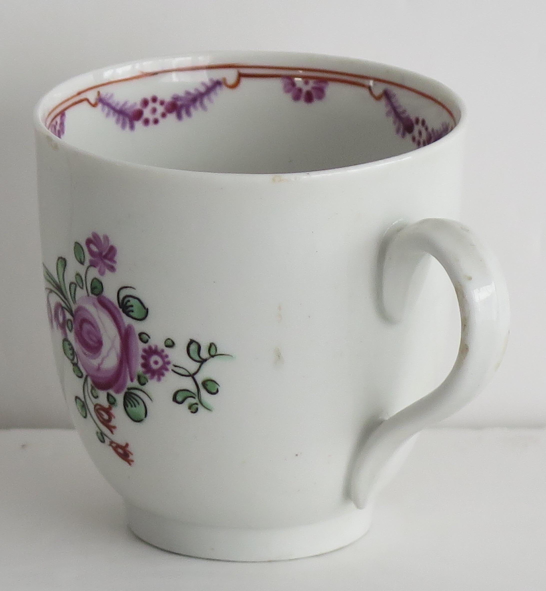 This is a hard paste porcelain coffee cup, by New Hall, dating to the late 18th century George 111rd period, circa 1790.

The piece is well potted on a low foot with a plain loop handle.

The cup is well decorated over-glaze with a very well