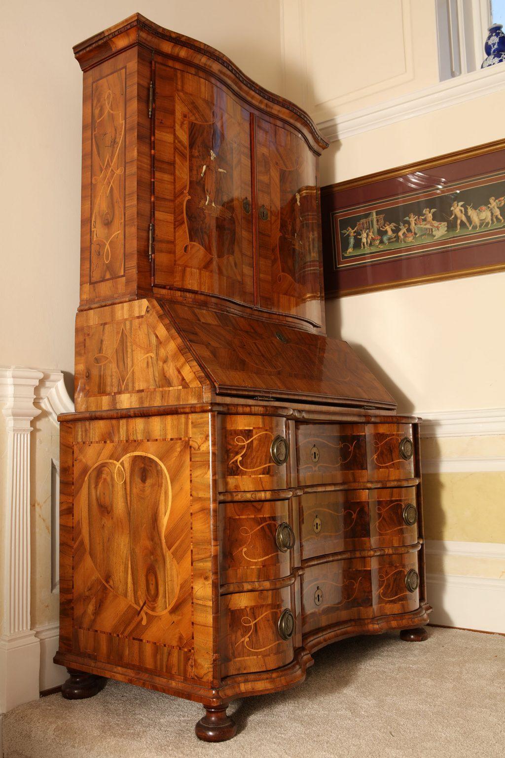 A fine mid-18th century bureau cabinet, the upper with two curved doors inlaid with two classical figures. Above a fall front opening to pigeon holes and drawers, above three serpentine long drawers with marquetry inlay, later ring handles with the