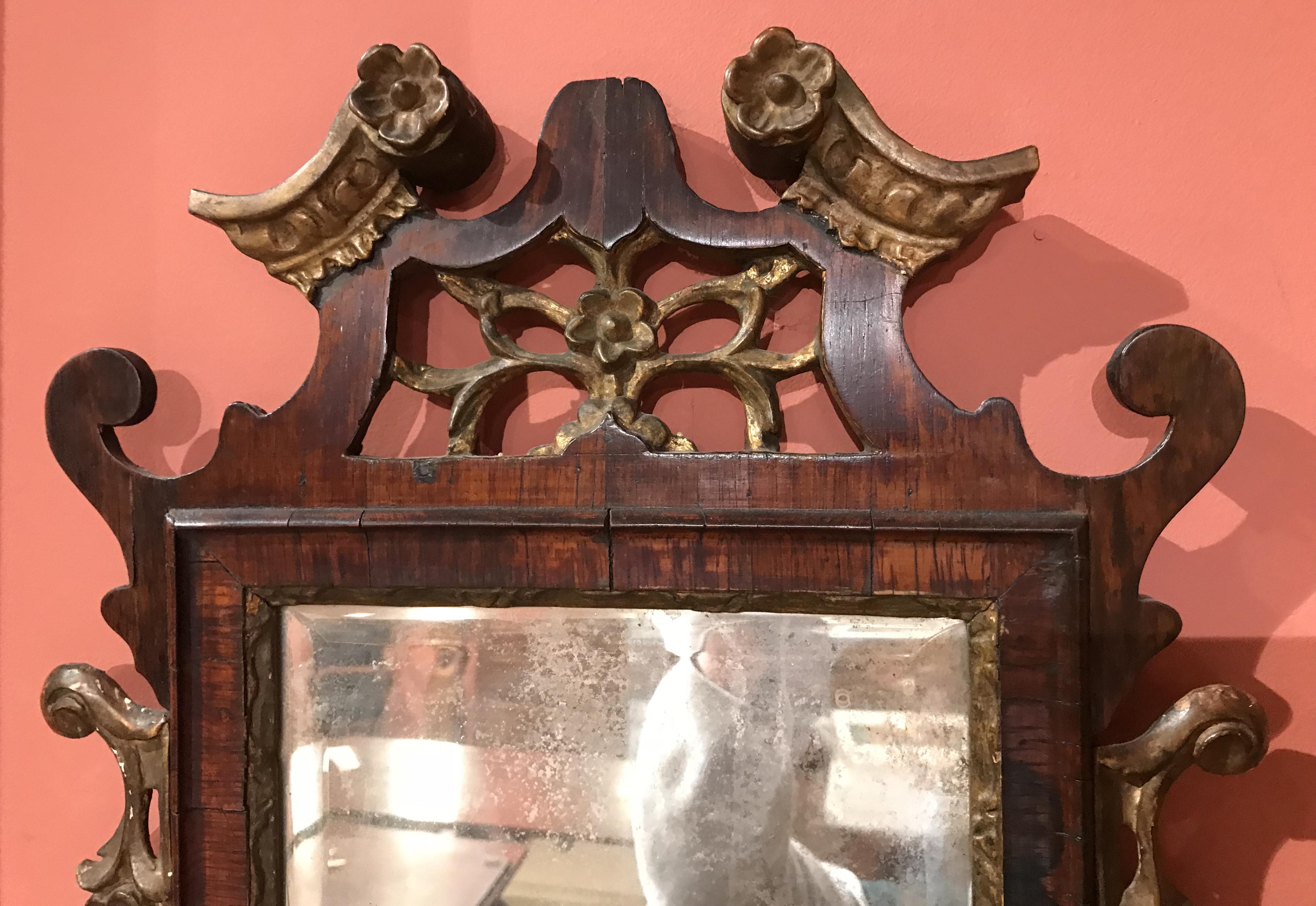 A fine diminutive rosewood mirror with carved reticulated crest and borders accented with gilt scrollwork and rosettes. Bevelled looking glass. Probably Northern European in origin, dating to the 18th century. Good overall condition, with minor