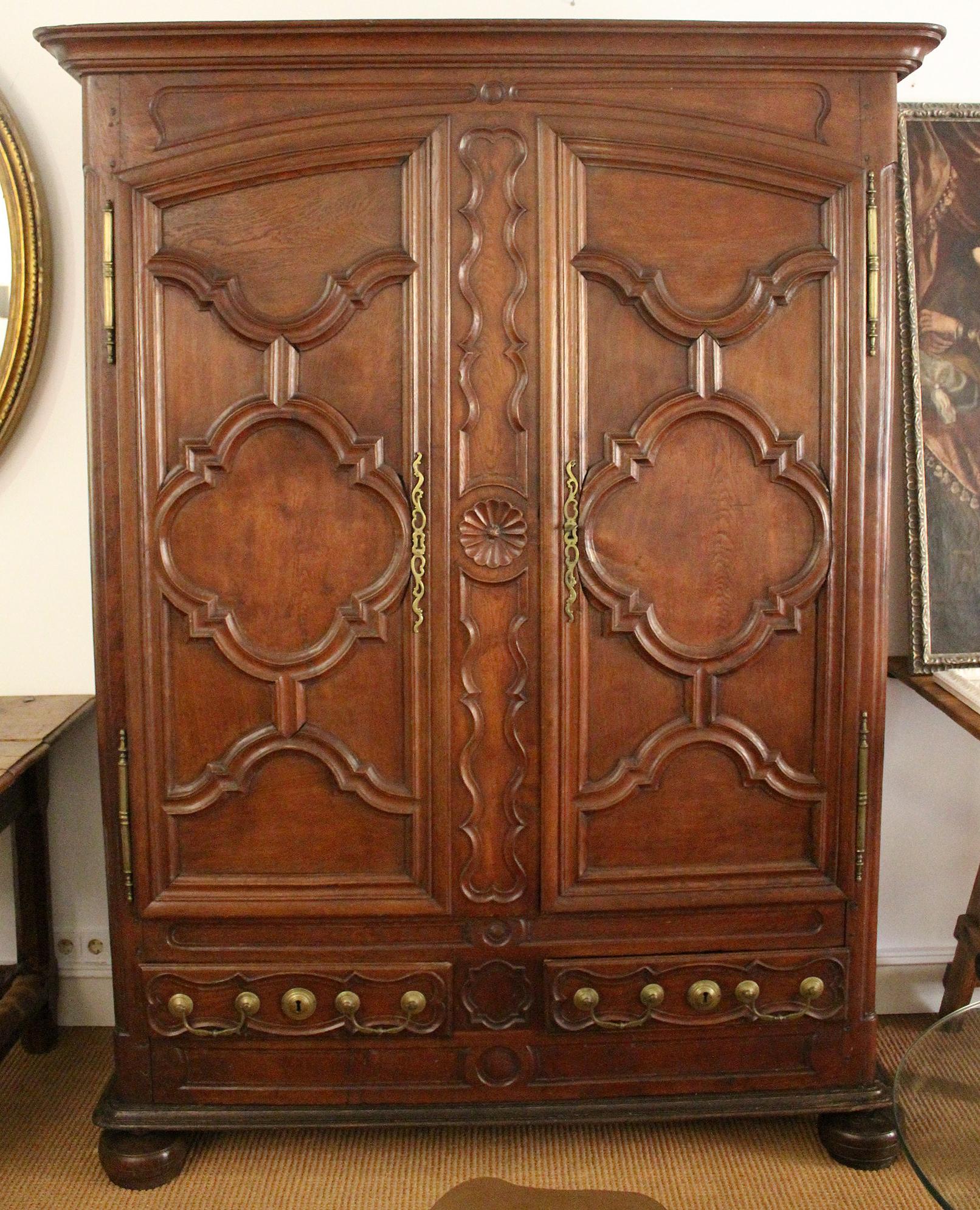 18t century northern France oak wardrobe with two doors and two drawers. Front and sides are decorated in neoclassical style hand carved reliefs with elegant fluted motifs and geometric shapes. High quality bronze fittings, all original, including