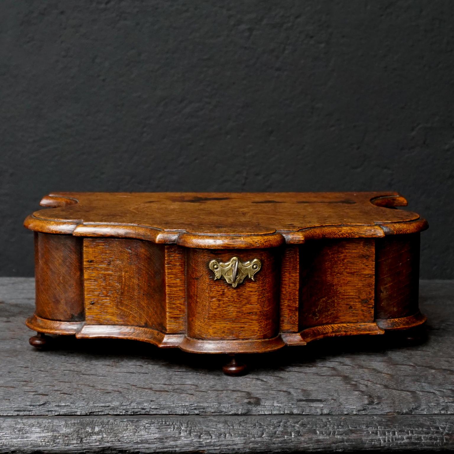 Very nice cartouche shaped 18th century oak plateau box with working lock and key.
Placed on 5 wooden feet.
Six compartments inside to keep little treasures safe.


 
 