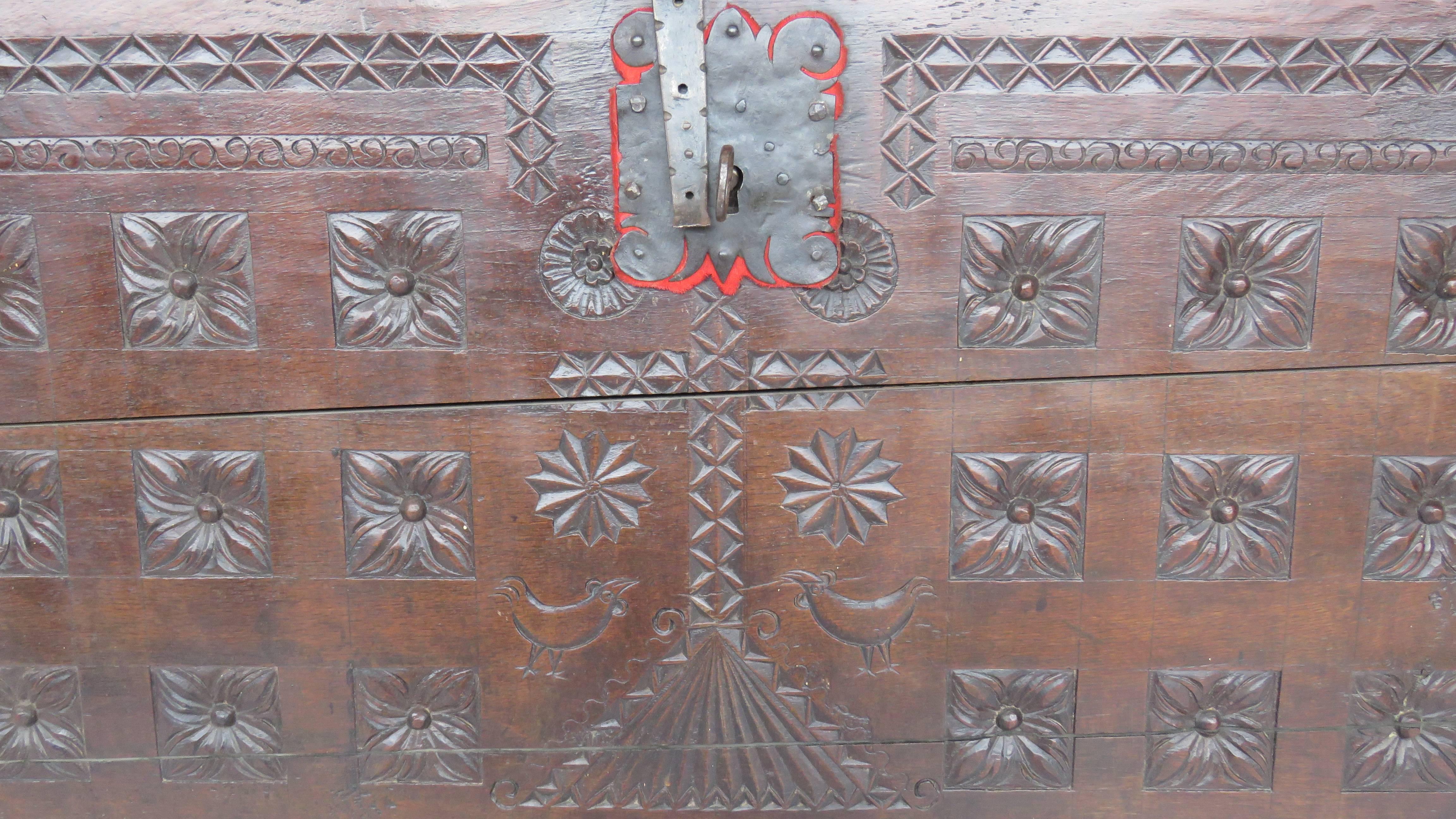 Rectangular hinged top over a deeply carved conforming case, front panel with geometric rosette motifs, centered by large chip carved cross, over scalloped apron, flanks carved with vertical grooves; original shield lock and hardware.
