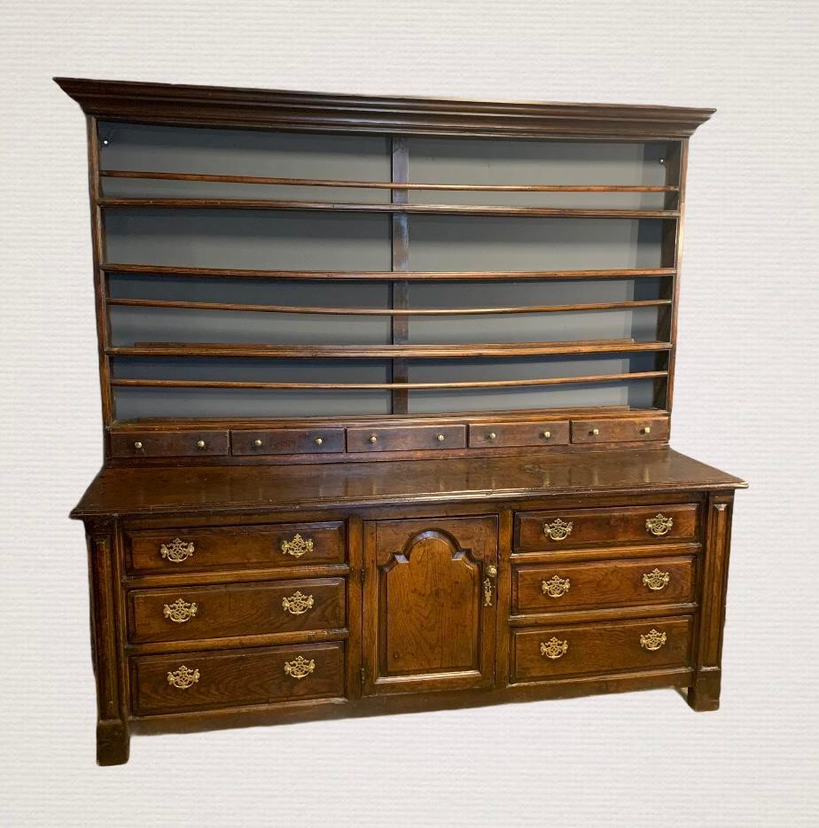 An 18th century oak dresser with original rack featuring plate retainers and five small drawers. The base with a shaped panelled cupboard to the centre and drawers either side. Good colour and patina.
  
