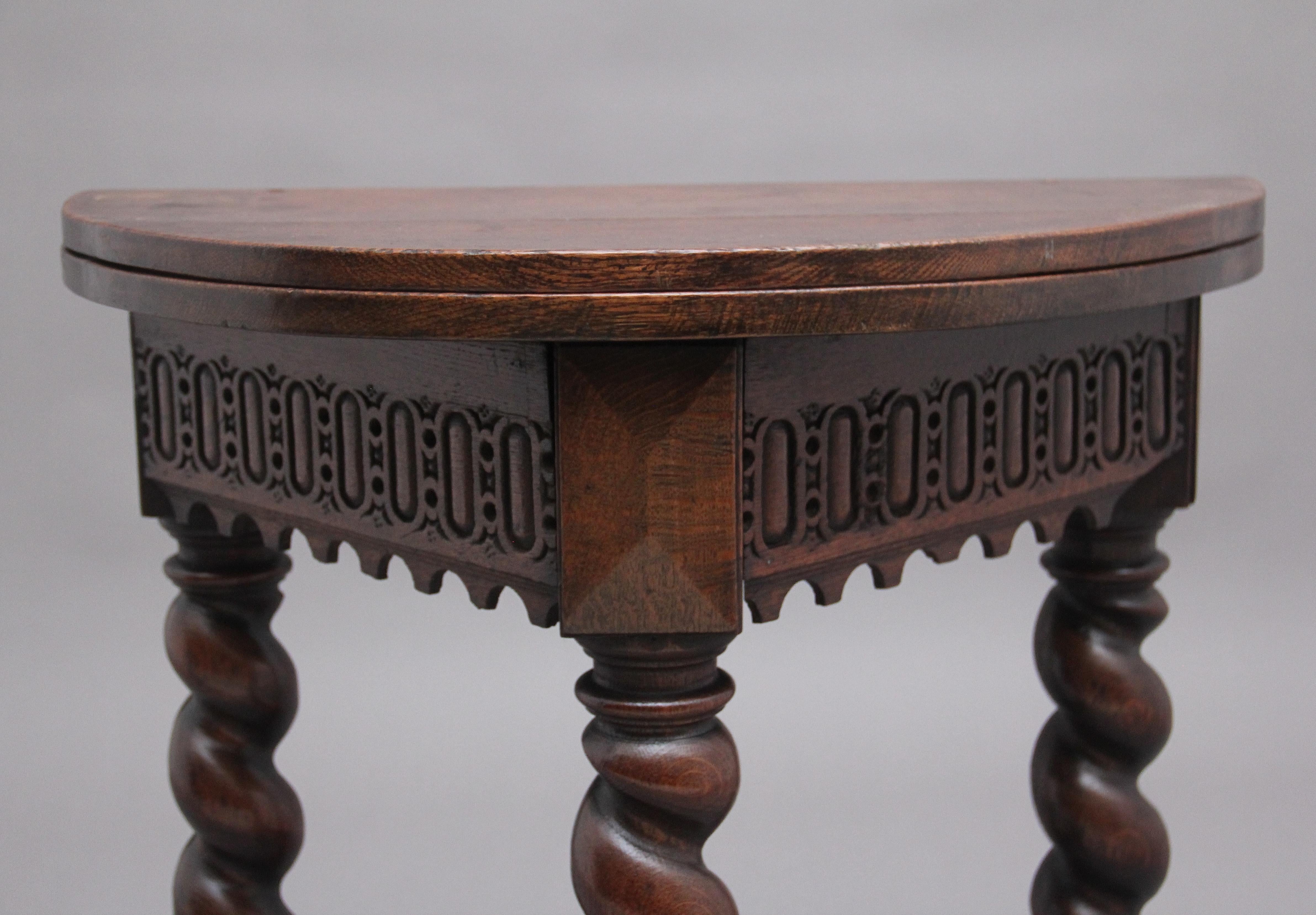 18th Century oak credence table, the hinged demi lune shape top above a deep frieze profusely decorated with intricate carving, supported on three bold barley twist legs terminating on turned feet and united by a stretcher, one of the rear legs fold