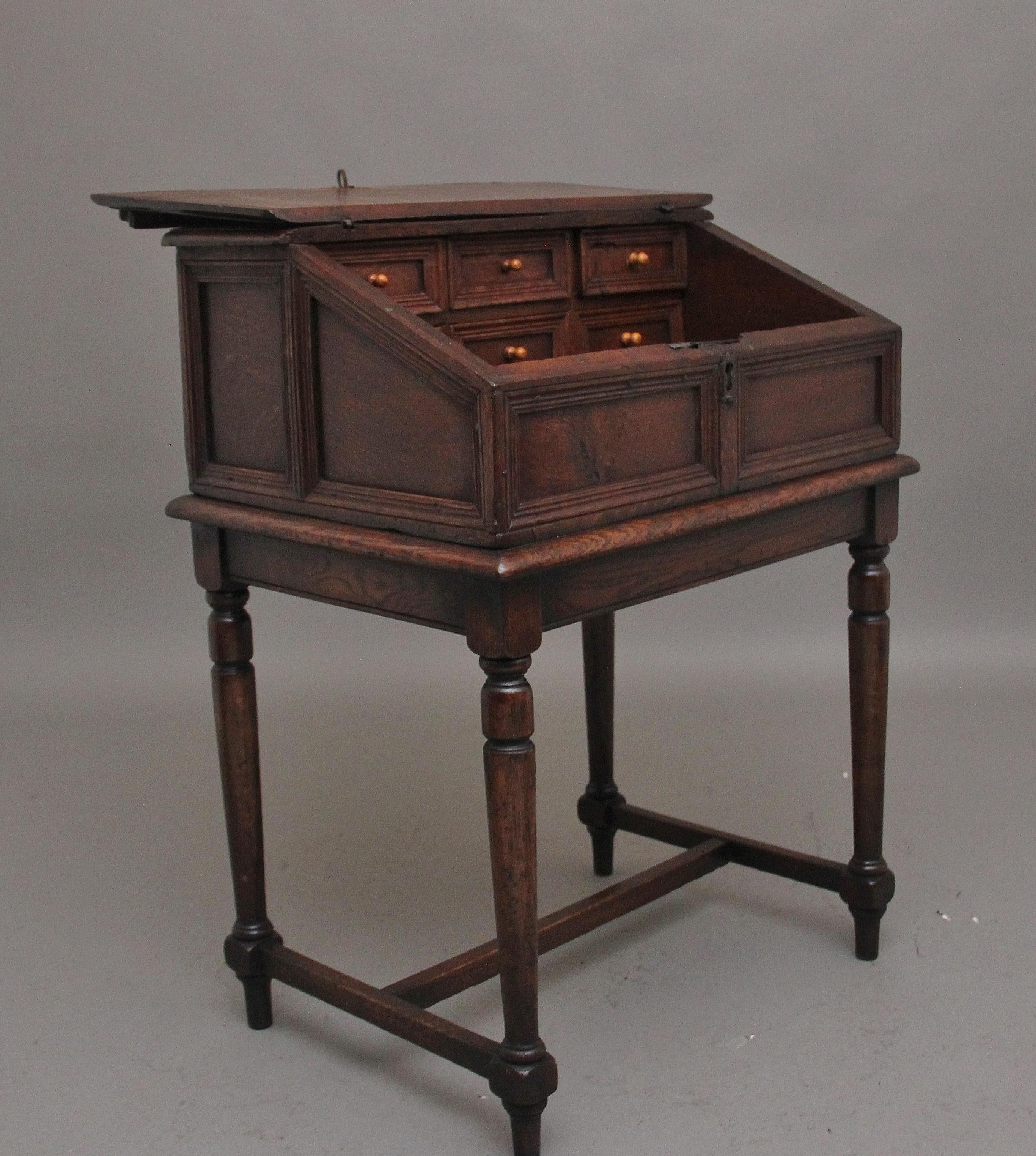 18th Century oak desk on later stand, the sloped desk having a hinged lift up lid opening to reveal a large compartment space with six moulded front drawers, the outside of the desk top having moulded panels along the front and sides, sitting on a