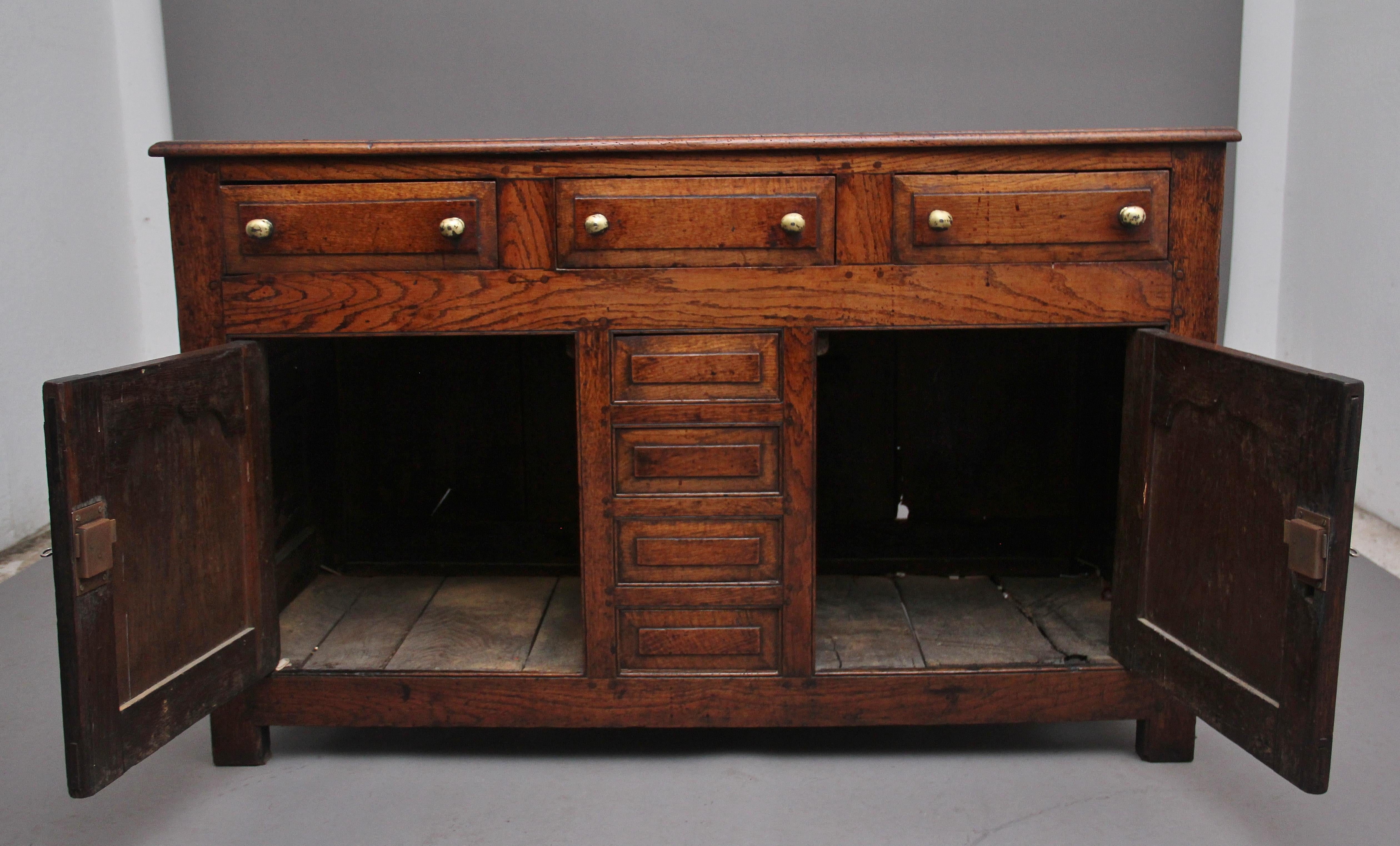 A superb quality 18th Century country oak dresser base, the moulded edge top above three drawers with turned brass knob handles, two cupboard doors below opening to reveal a large storage space, the cupboard doors having decorative fielded panels,