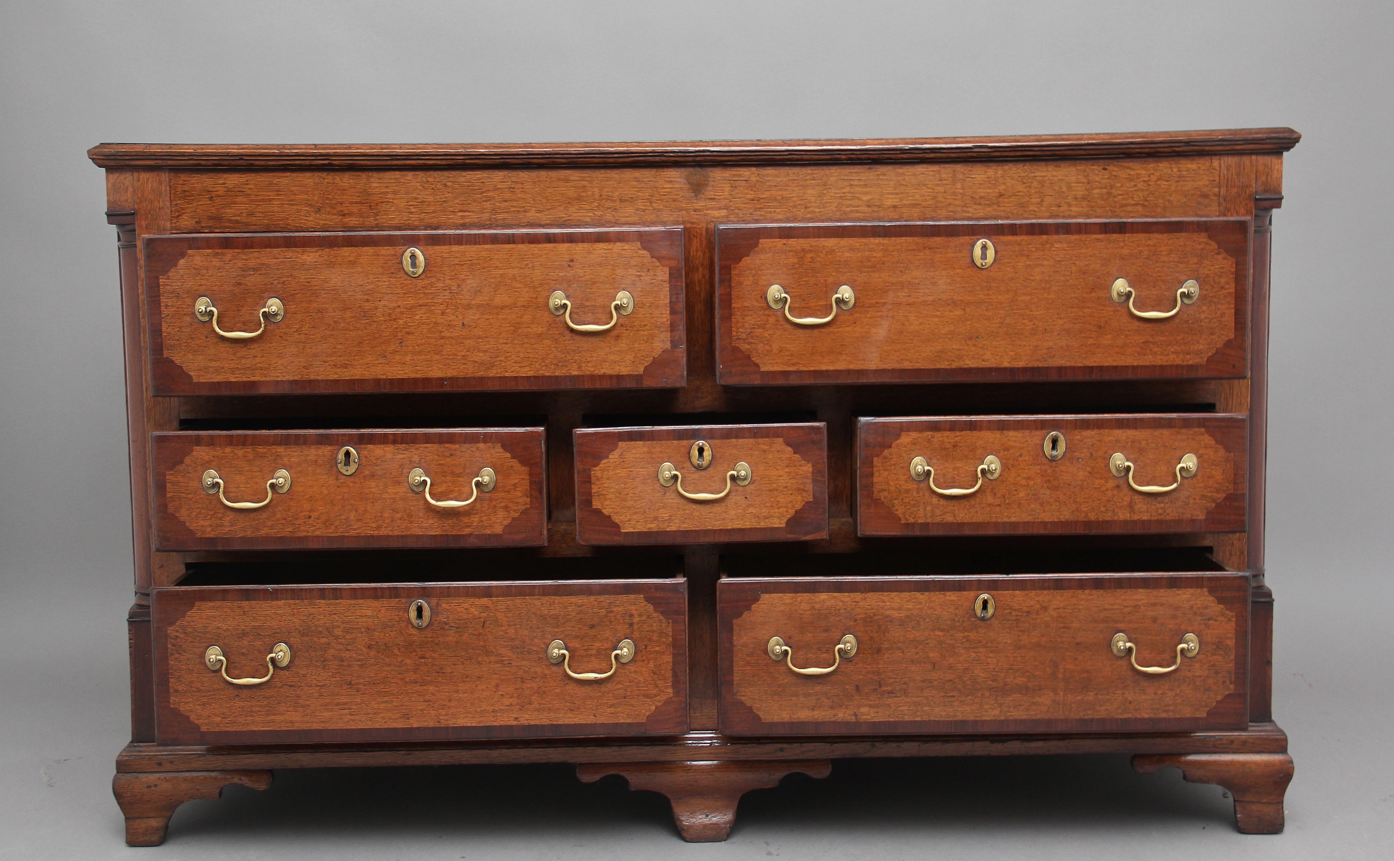 18th century oak dresser base / chest, the moulded edge top crossbanded in mahogany above a selection of seven drawers having brass swan neck handles, the drawer fronts are also crossbanded, on the front corners there are turned quarter columns in