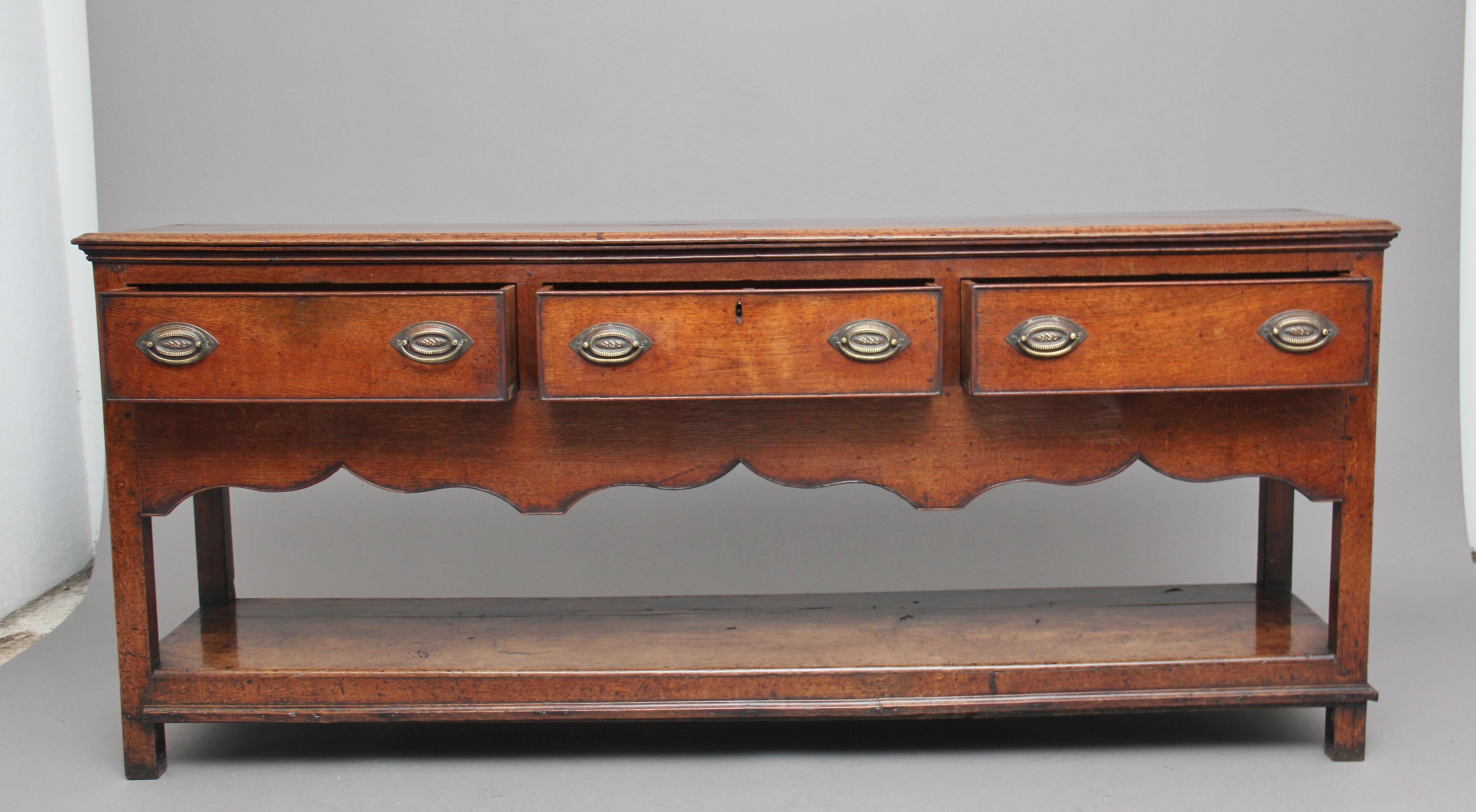 18th century oak potboard dresser base, the moulded edge rectangular top over three deep drawers with oval brass plate handles, having a lovely beaded shaped frieze, supported on square legs united by a potboard. Lovely color and in great condition,
