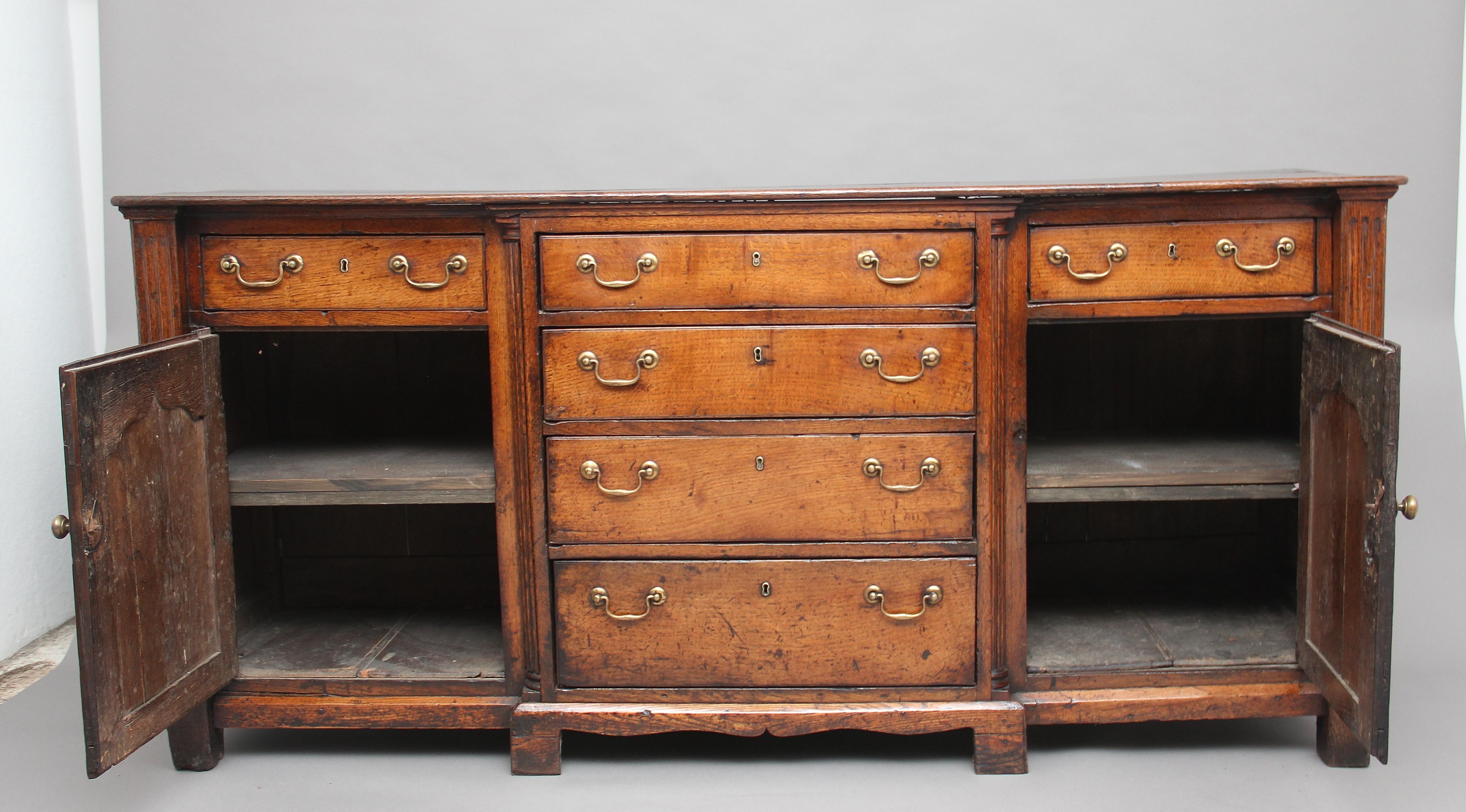 Mid-18th century oak dresser, the rectangular top above a selection of six oak lined drawers, all with original brass swan neck handles, cupboard doors either side with fielded panels, opening to reveal a single shelf inside, fluted columns at each