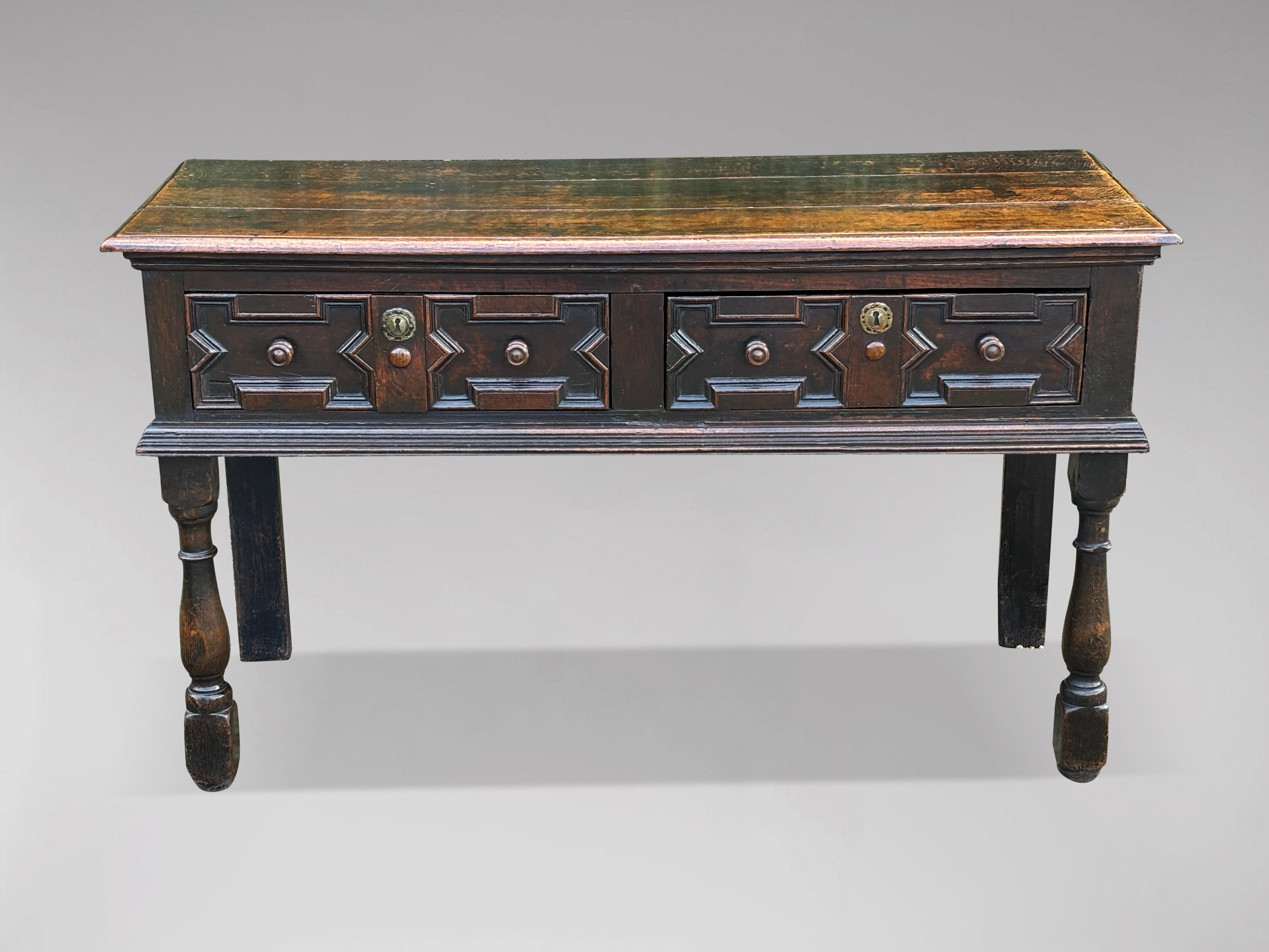 A lovely size, early 18th century oak dresser base with two drawers over geometric moulded detail. A moulded three planked solid oak top and the front of the dresser features geometric applied mouldings to the drawer fronts. The two large working