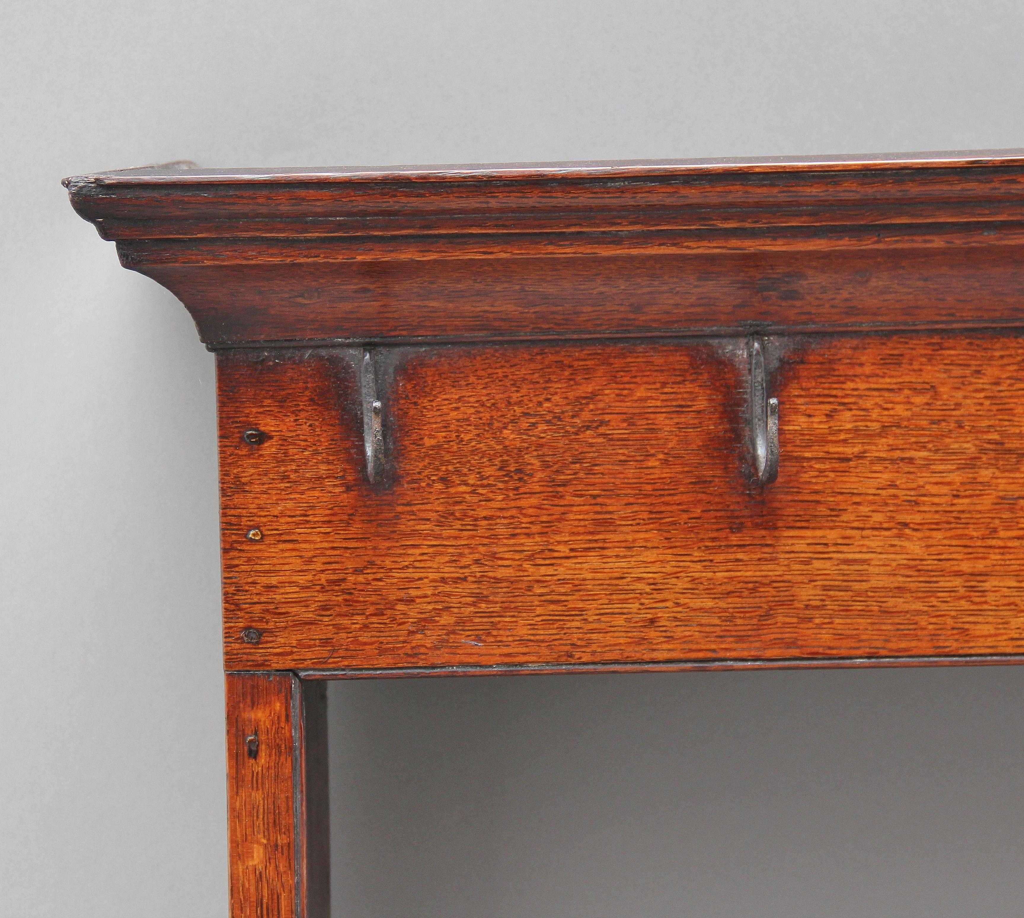 18th century oak hanging rack, the molded cornice above a frieze rail with cup hooks, two open shelves with the top shelf also having cup hooks, shaped end supports. Lovely color, circa 1780.
 