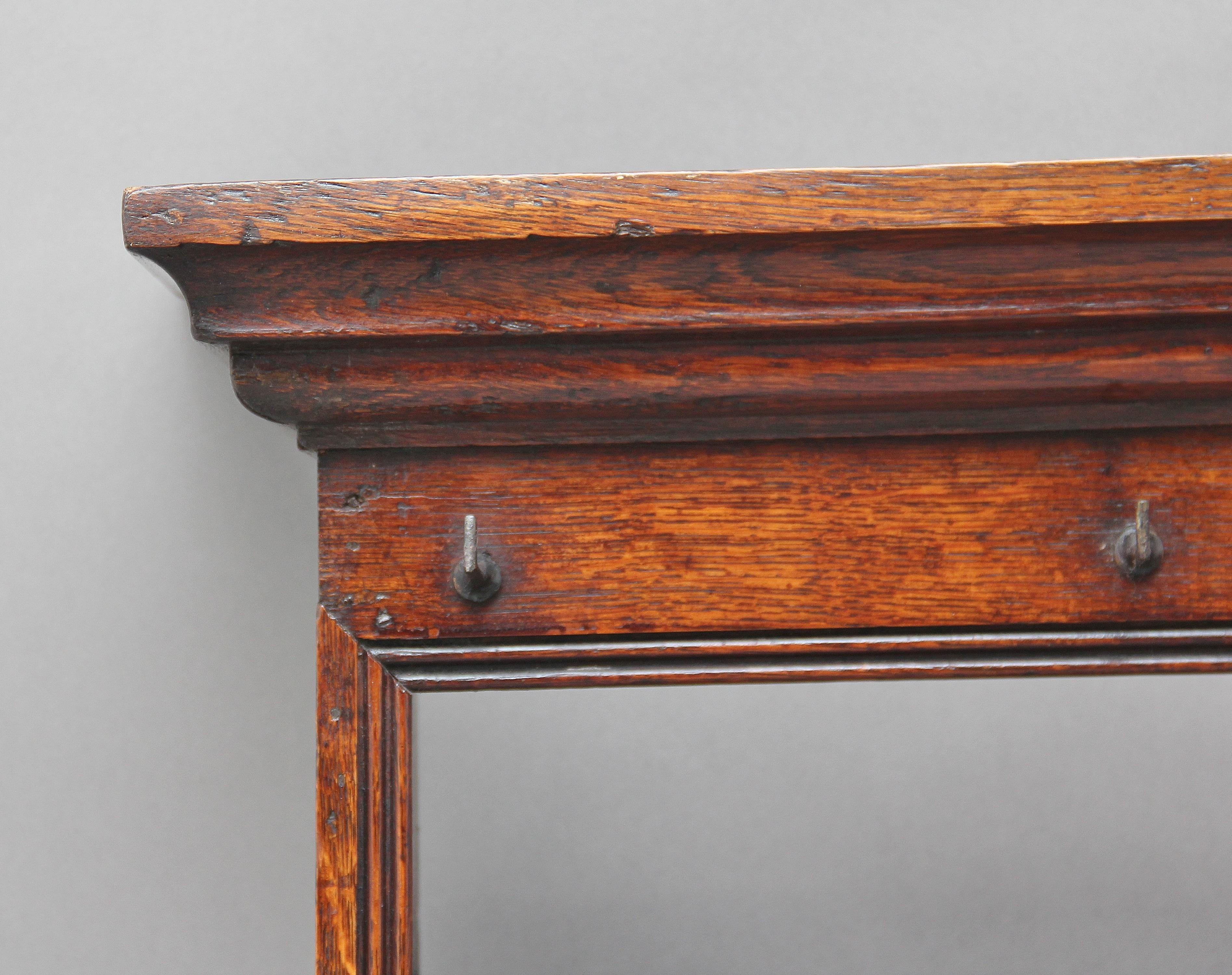 18th century oak hanging rack, the moulded cornice above a frieze rail with cup hooks, two reeded front open shelves with plate grooves and also having cup hooks, shaped end supports, circa 1780.
   