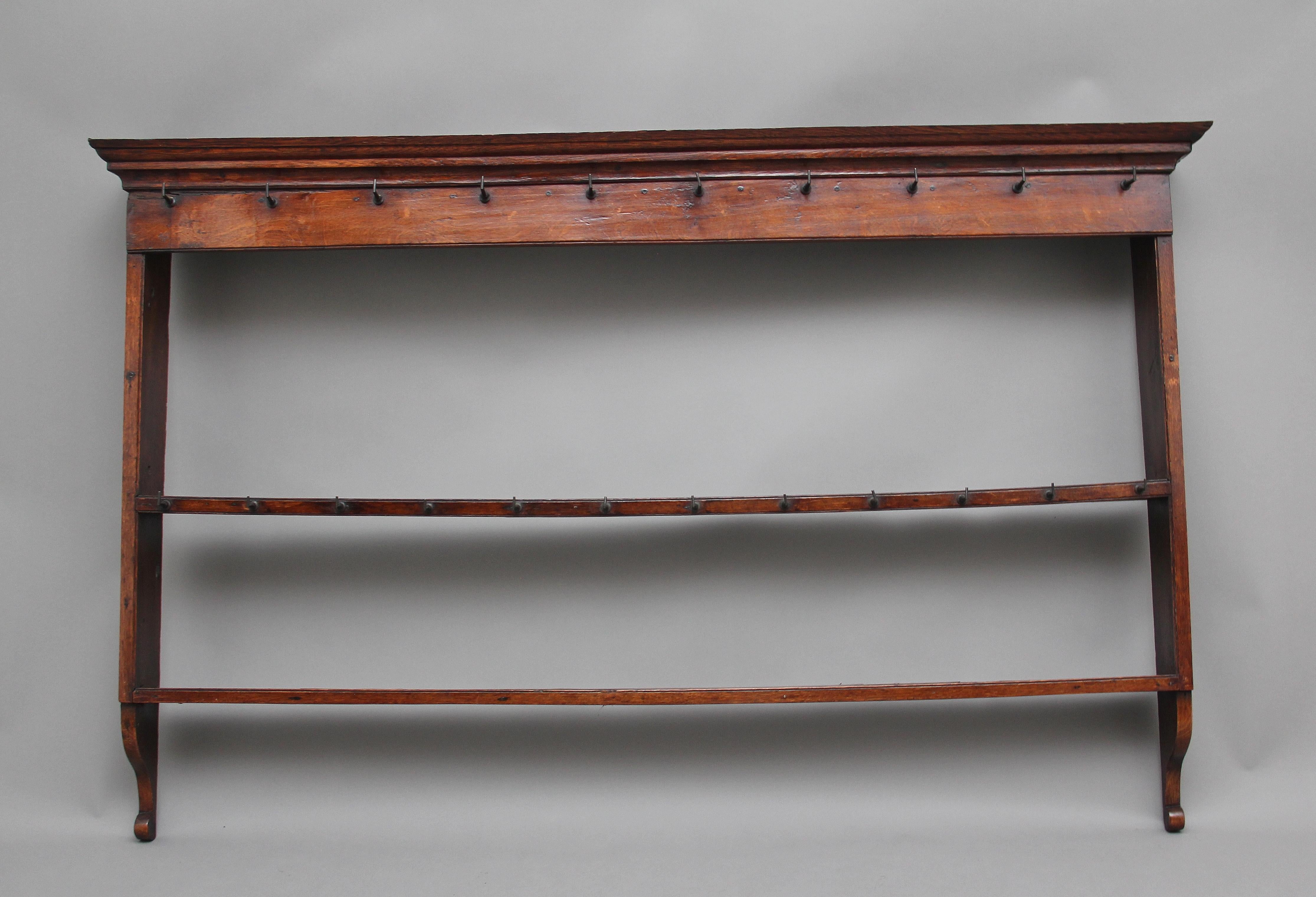 18th century oak hanging rack, the moulded cornice above a frieze rail with cup hooks, two open shelves with the top shelf also having cup hooks, shaped end supports. Lovely color, circa 1780.
      