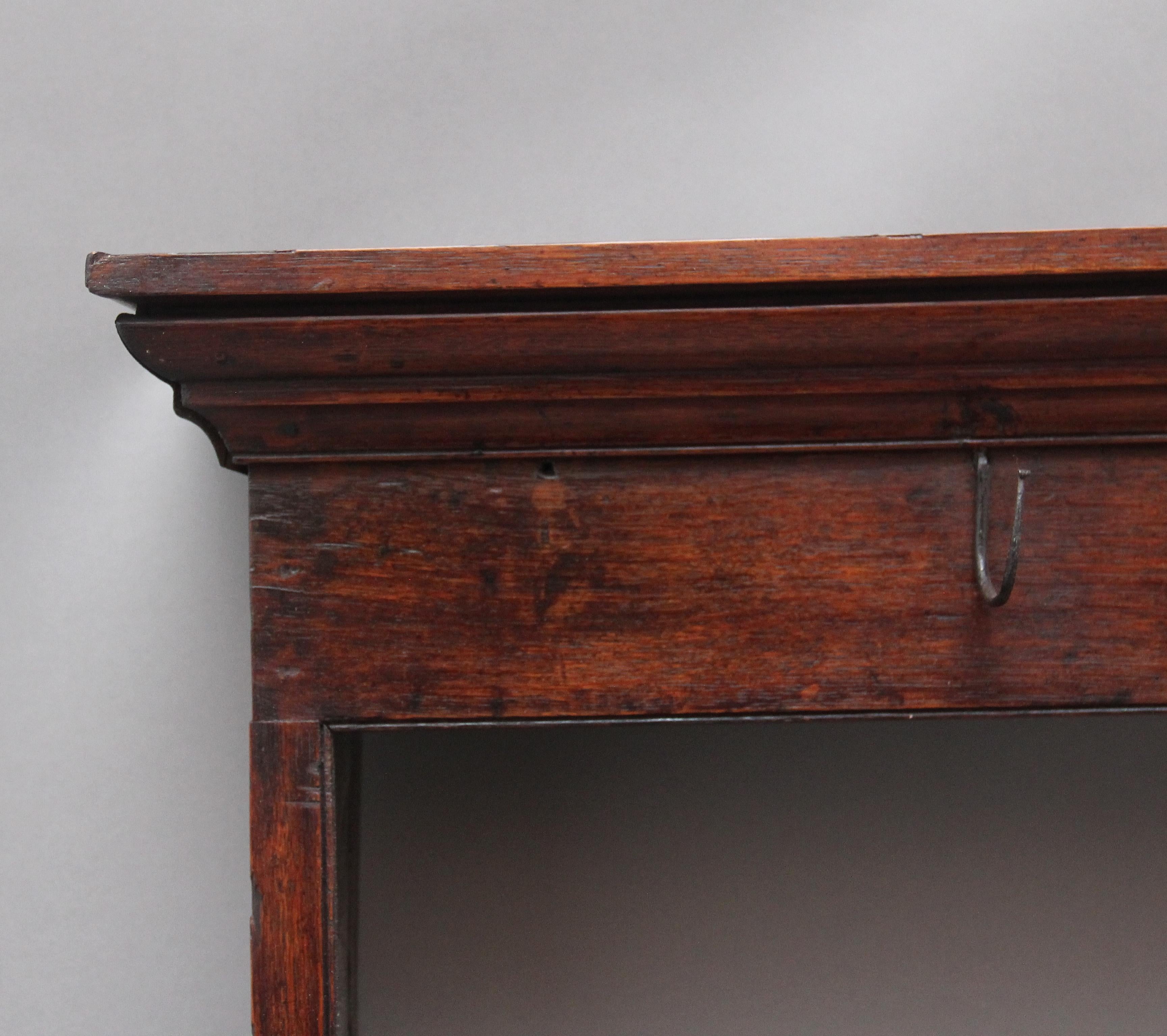 18th century oak hanging rack, the moulded cornice above a frieze rail with cup hooks, two open shelves with the top shelf also having cup hooks, shaped end supports. Lovely colour. Circa 1780.
 
