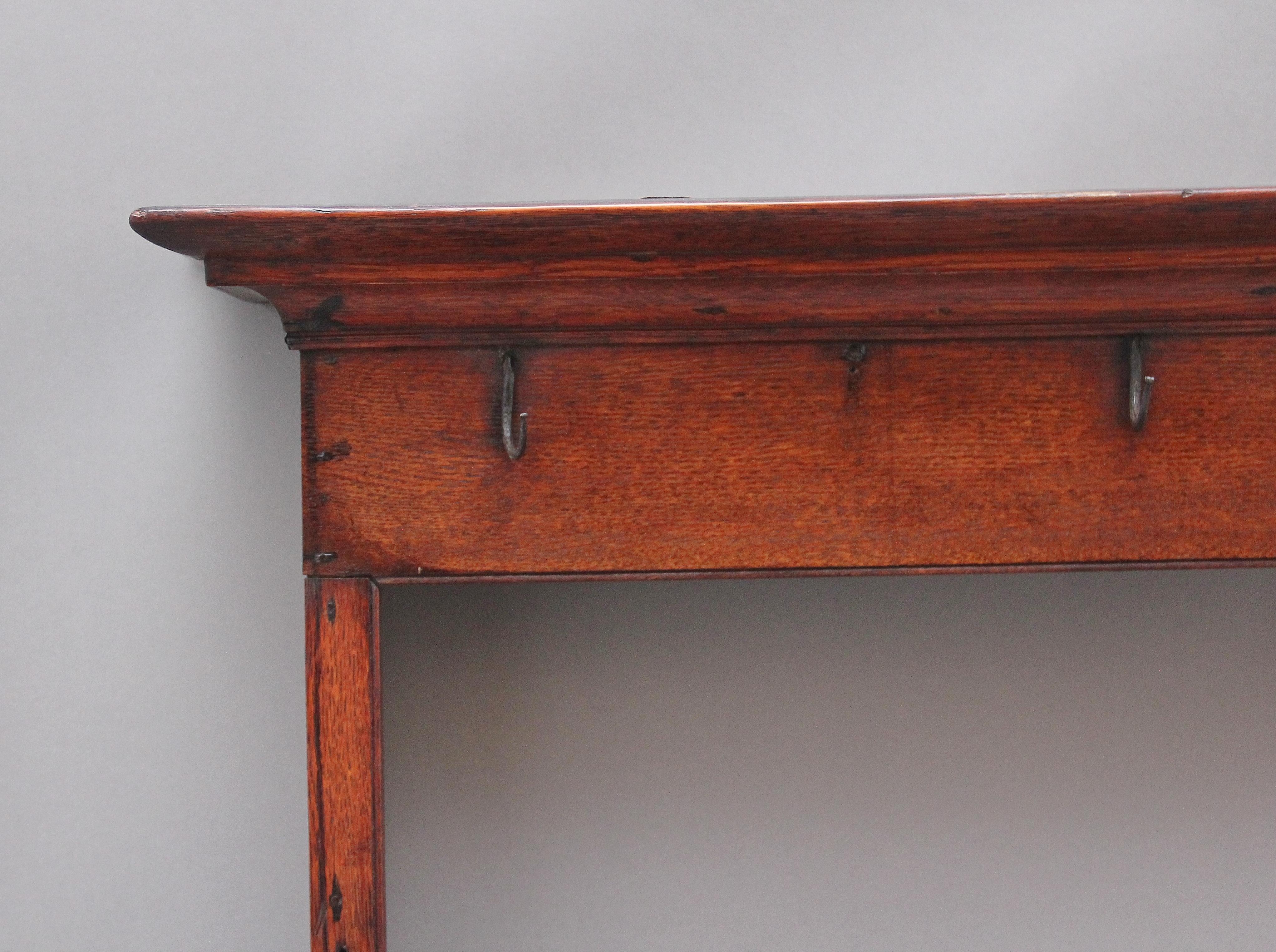 18th Century oak hanging rack, the moulded cornice above a frieze rail with cup hooks, two open shelves with the top shelf also having cup hooks, shaped end supports. Lovely colour. Circa 1780.
 