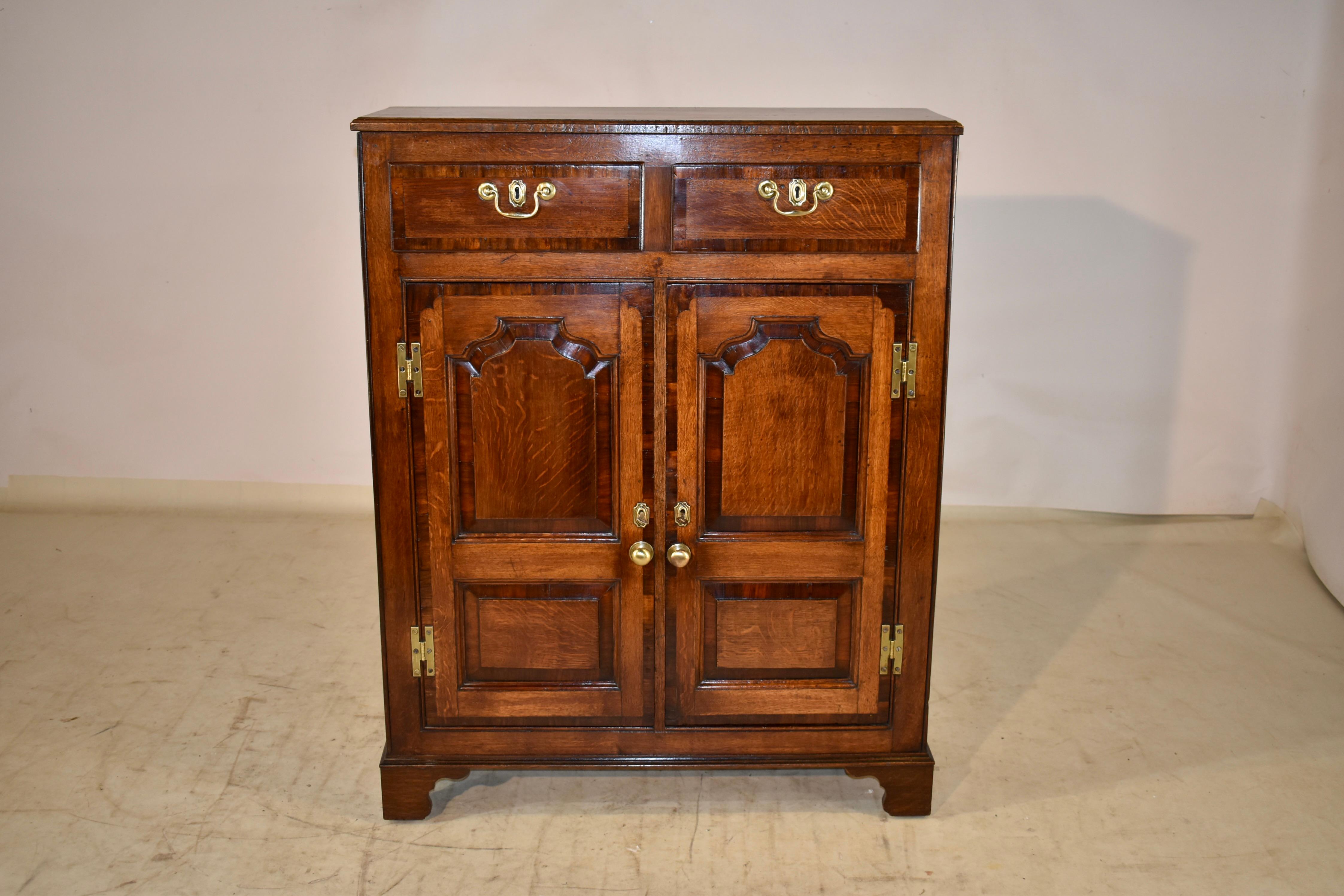 18th century oak and mahogany wall cupboard from the Lancashire region of England. The top has a molded edge and sits atop a gorgeous case. The sides are simple, and there are two drawers in the front, both banded in mahogany for added design