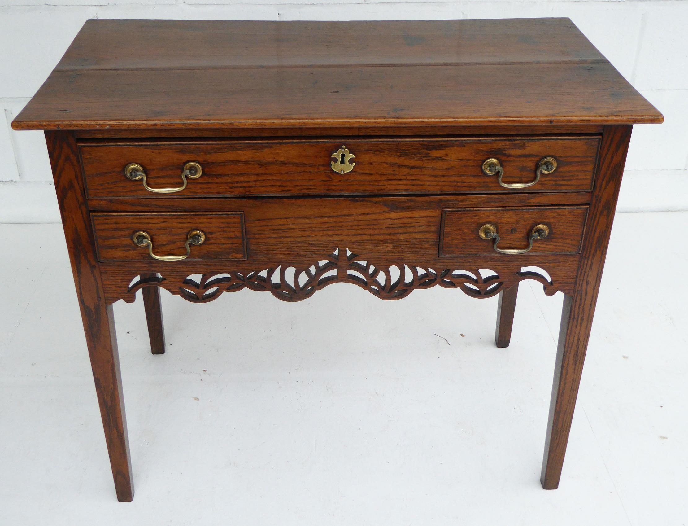 For sale is a good quality 18th century oak lowboy. This piece has an arrangement of four drawers, one long drawer at the top with one short drawer below on either side. Below this is an ornate fretwork frieze. The lowboy stands on four square