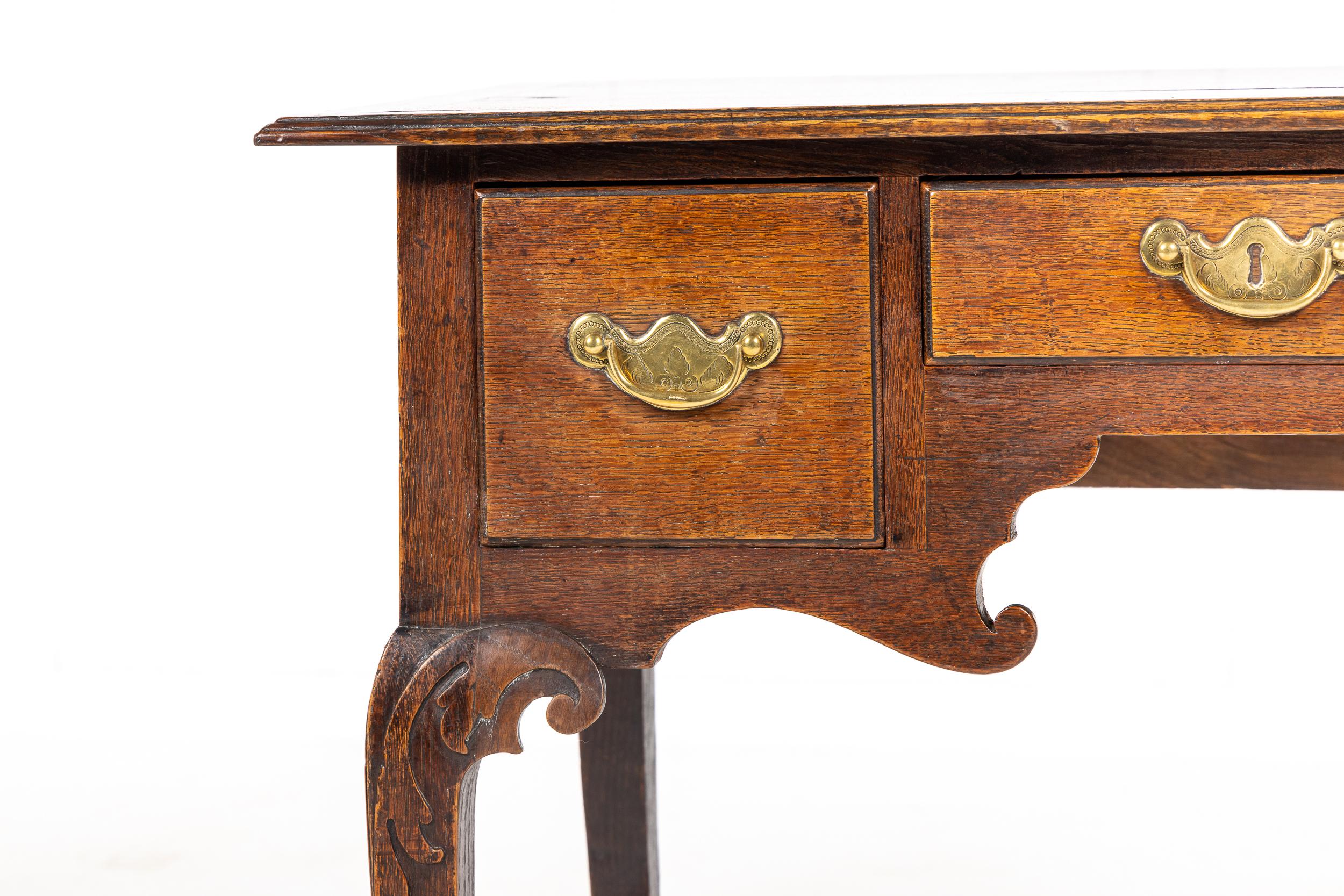 18th century oak lowboy with moulded edge top. Having three drawers with original brass handles, with a lovely carved, shaped apron below. Raised on long, shapely cabriole legs with intricately carved knees terminating in pad feet.

Excellent