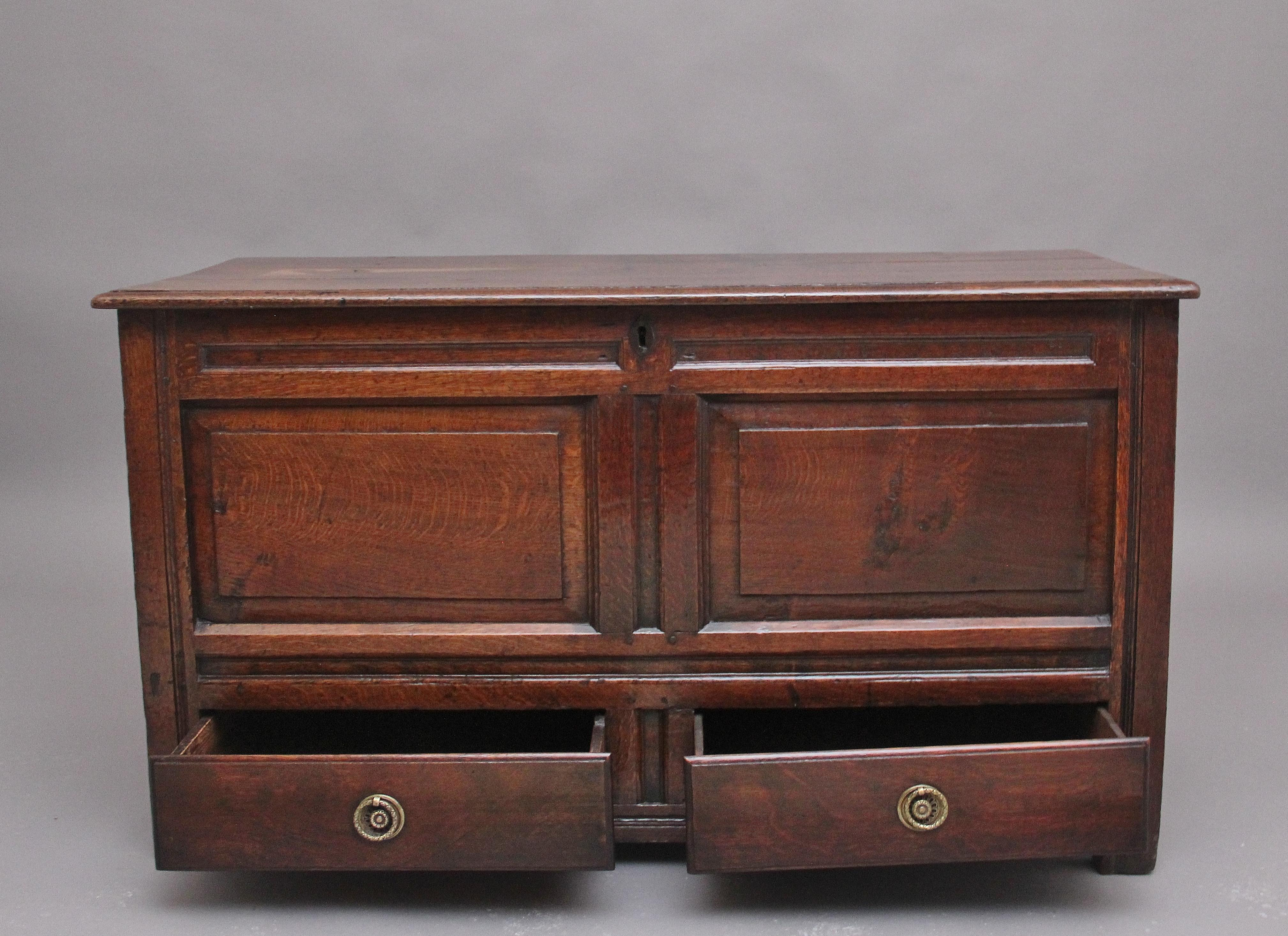 18th Century oak mule chest, the rectangular top opens on the original steel hinges to reveal a large compartment space which includes a candle box to the left, panelled sides and having fielded panels to the front of the chest with two drawers at
