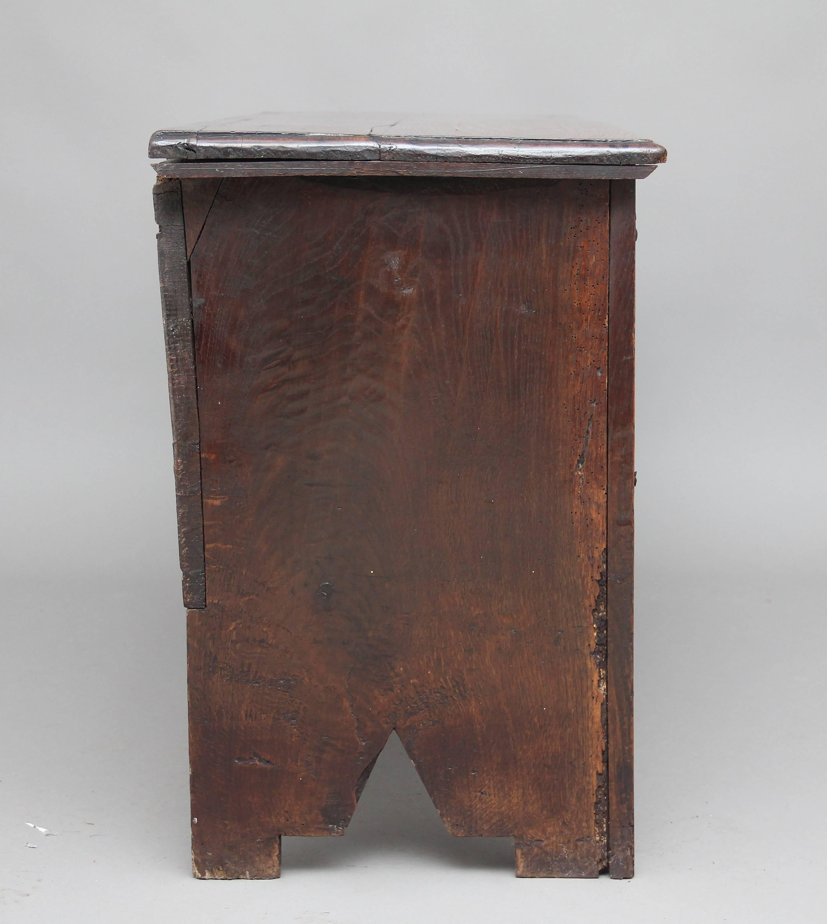 18th century oak plank coffer with the hinged top above a three panelled front with carved decoration, wonderfully carved rails, standing on square legs, circa 1720.