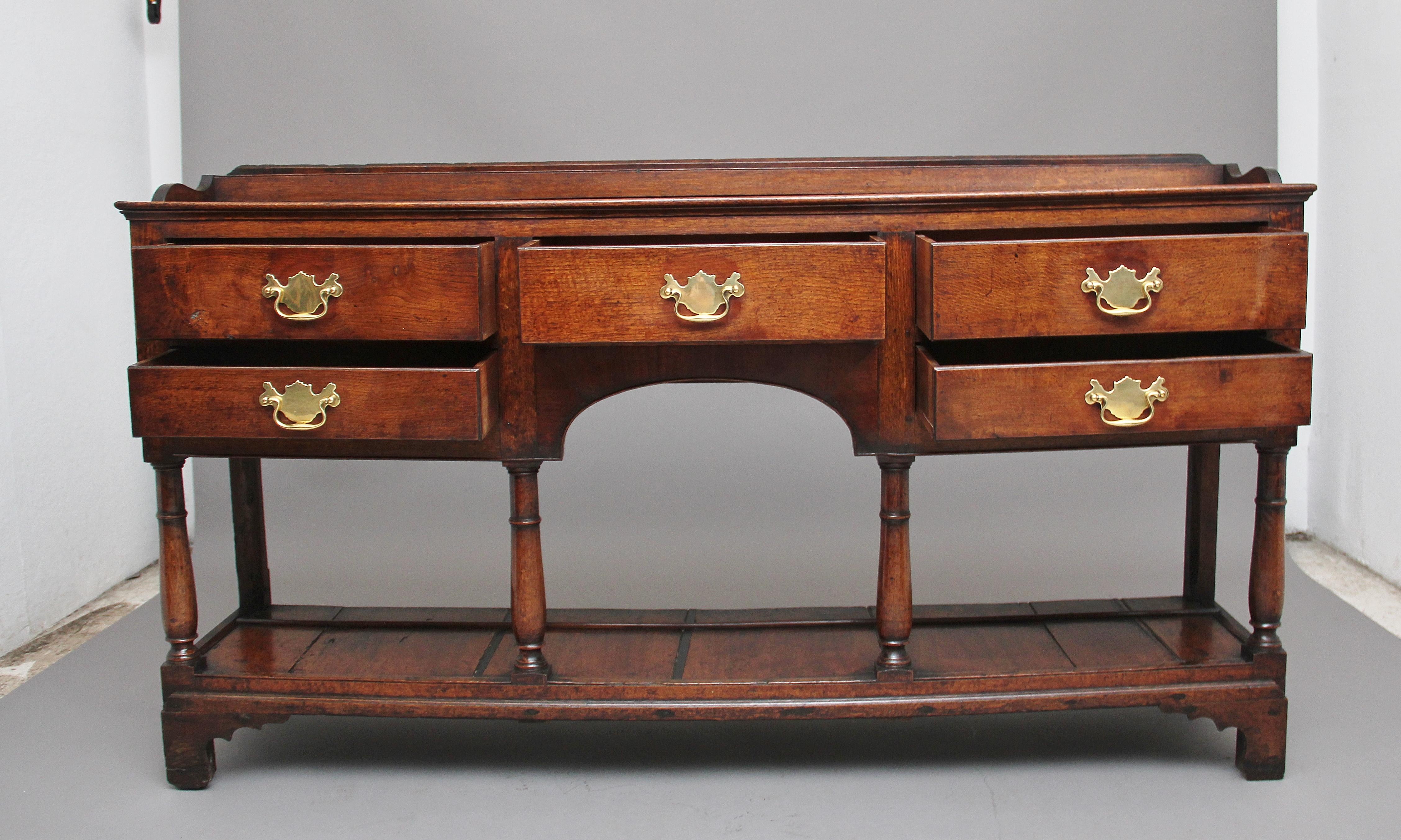 18th century oak potboard dresser, the rectangular top above a selection of five drawers with brass plate handles, having an arched frieze with a beaded edge with front turned column supports terminating onto a potboard, standing on square feet.